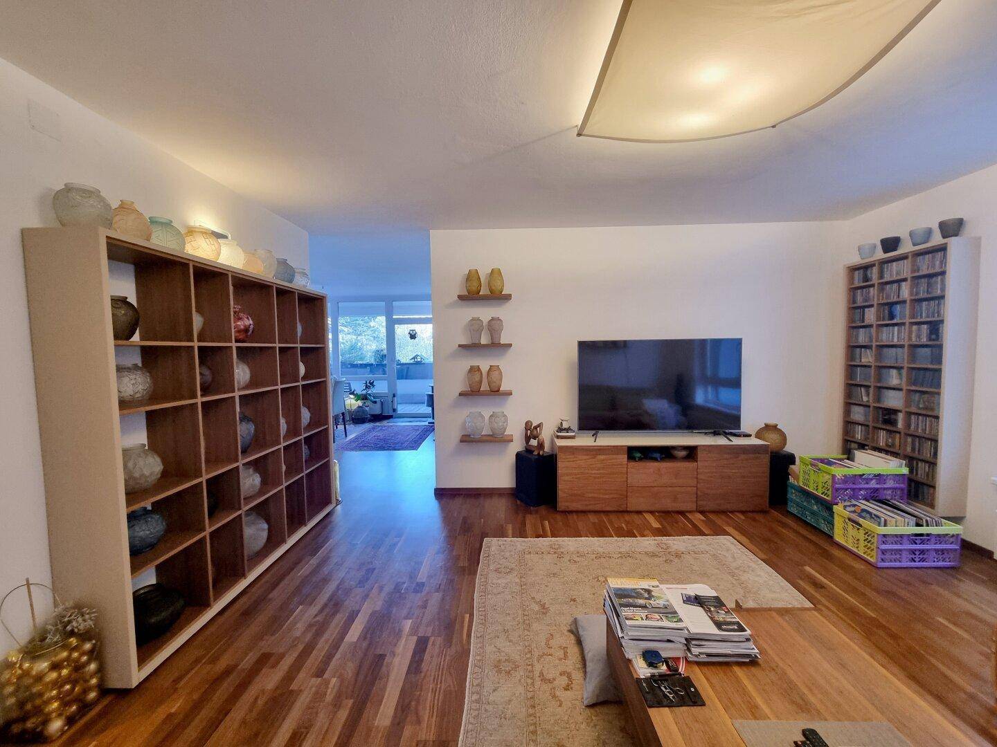 Geräumiges Wohnzimmer mit Holzboden, Bücherregalen und dekorativen Vasen.
