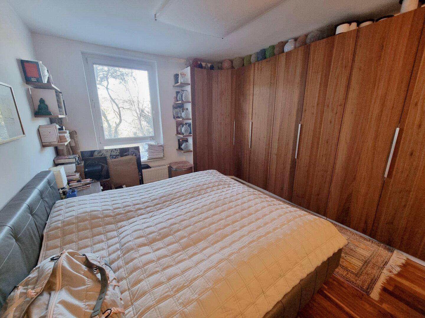 Schlafzimmer mit großem Bett, Holzboden und Einbauschränken aus Holz.