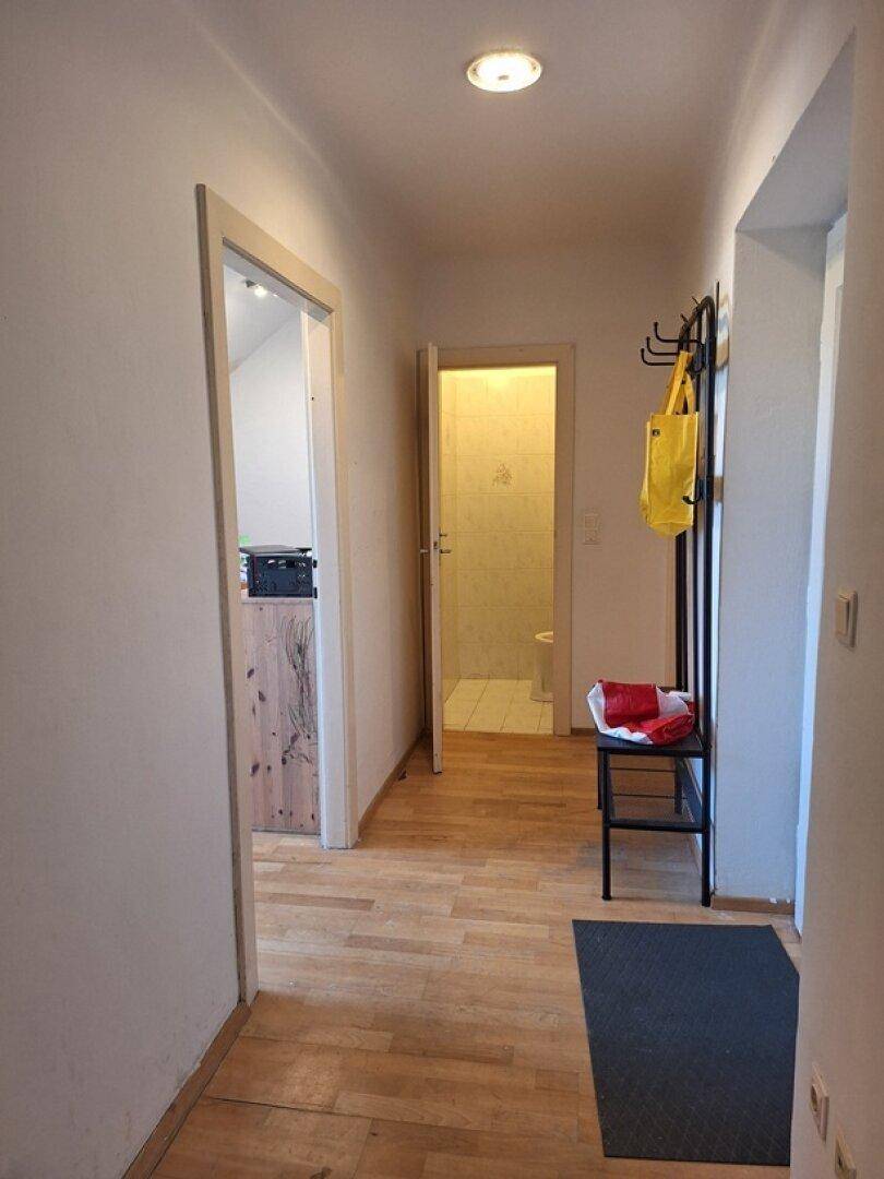 Heller Flur mit Holzfußboden und Garderobe, der zu weiteren Räumen führt.