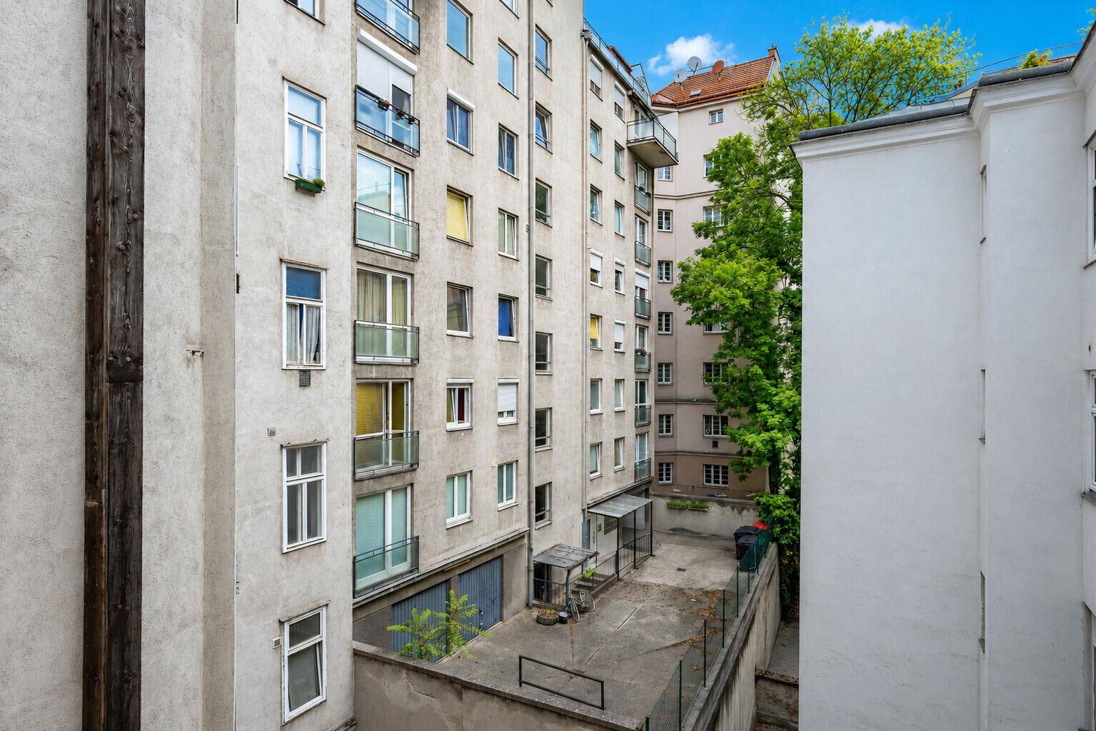 Blick auf den Innenhof eines Mehrfamilienhauses mit mehreren Balkonen und Fenstern.