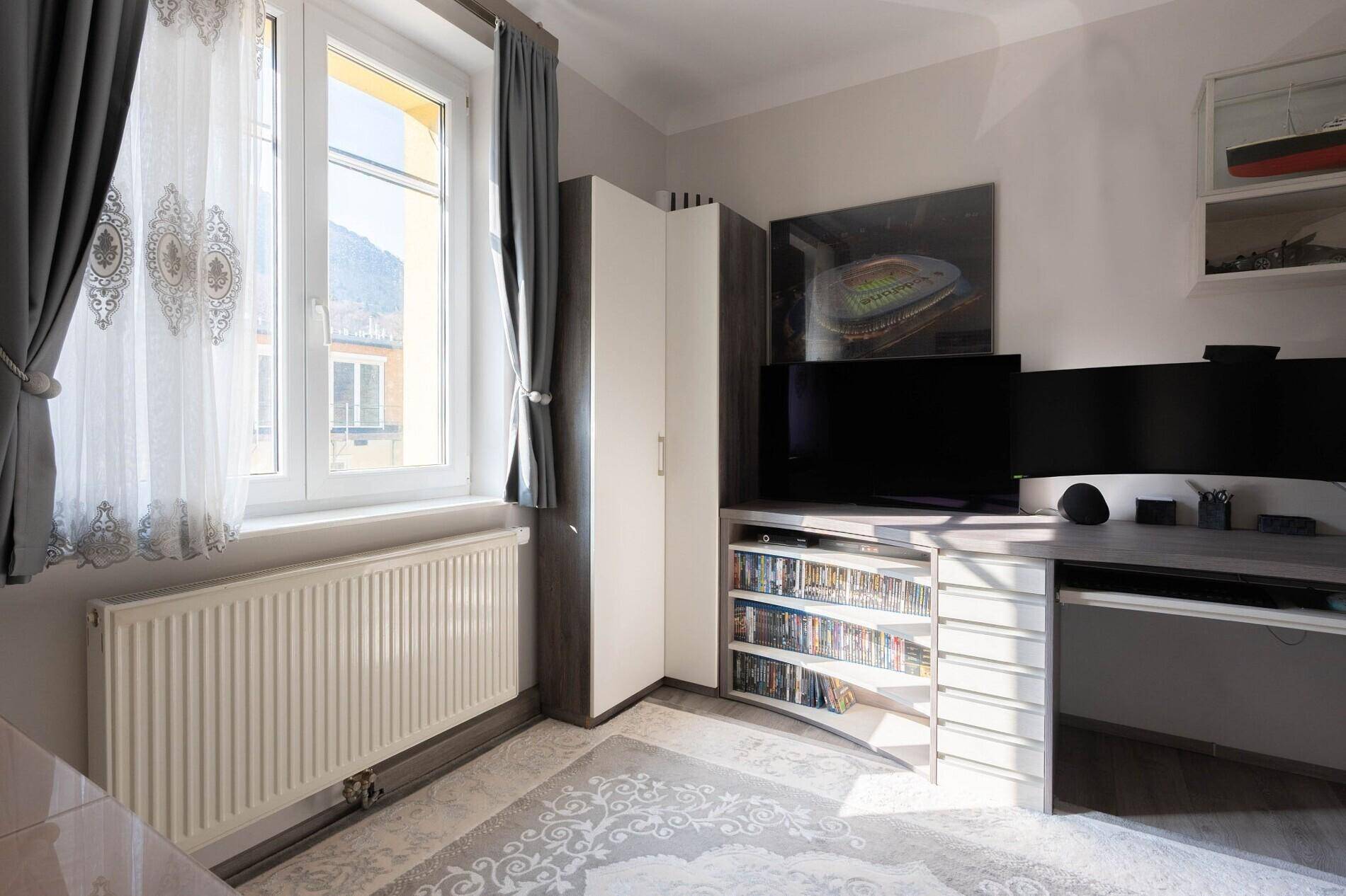 Arbeitszimmer mit Schreibtisch, Computermonitoren und Fenster mit Blick ins Grüne.