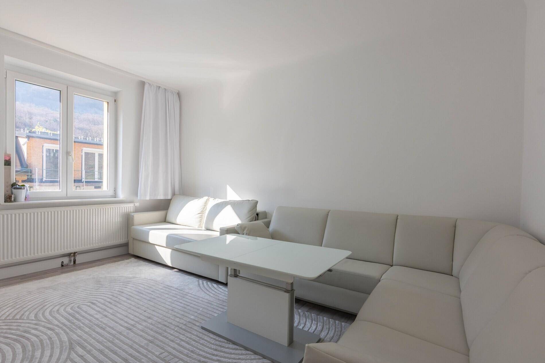 Geräumiges Wohnzimmer mit großem Ecksofa, Couchtisch und hellem Teppich.