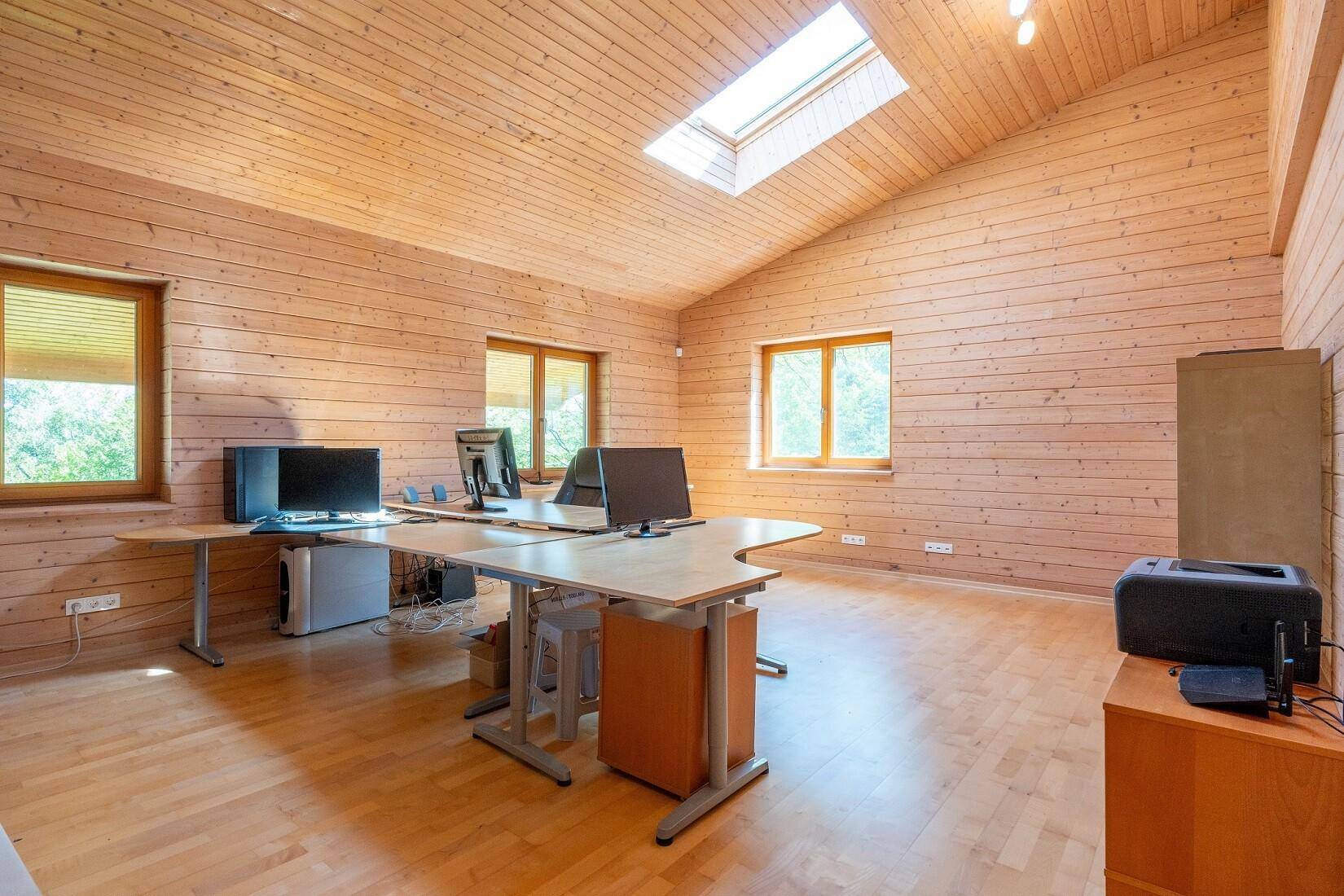 Geräumiges Büro mit Holzwänden, Dachschräge, Dachfenster und mehreren Arbeitsplätzen.