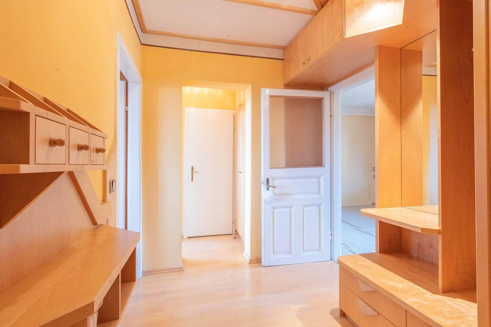 Heller Flur mit Holzvertäfelung, Laminatboden und mehreren Türen.