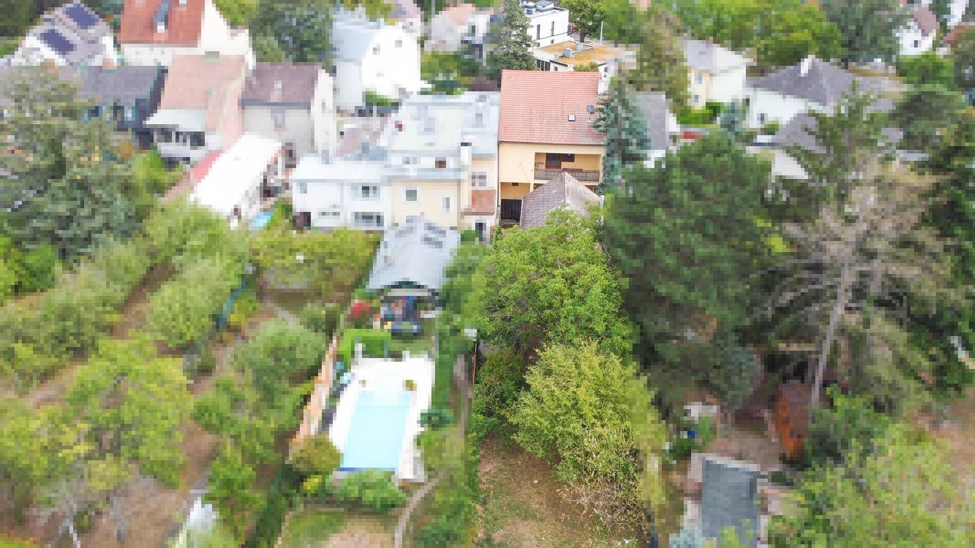 Luftaufnahme einer Wohnsiedlung mit Häusern, Gärten und einem Swimmingpool.