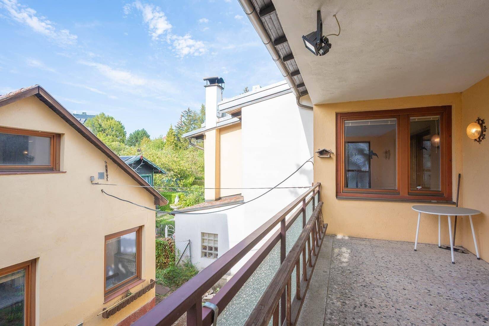 Langer Balkon mit Geländer, kleinem Tisch und Blick auf die Umgebung.