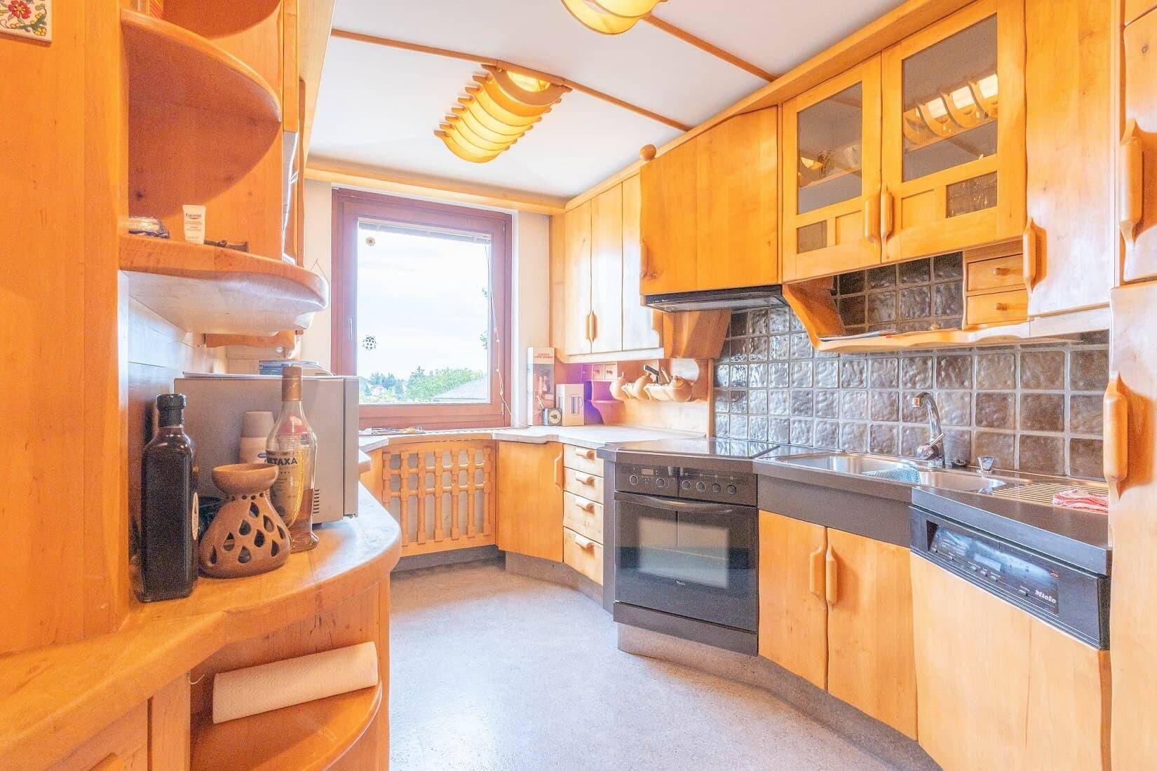 Rustikale Holzküche mit Einbaugeräten, Fliesenrückwand und Fensterblick.