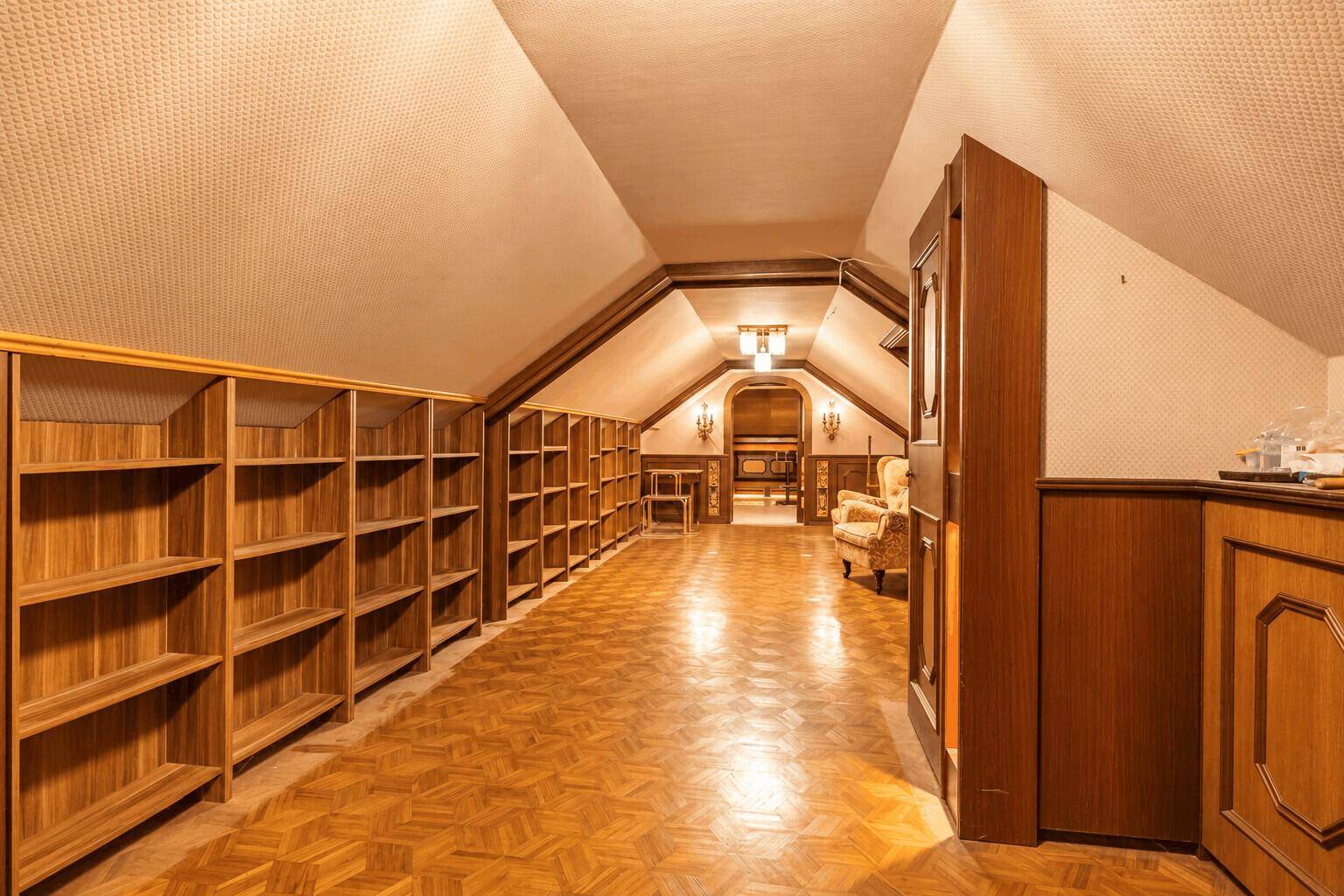 Geräumiger Dachboden mit Holzboden, Einbauregalen und gemütlicher Sitzecke.