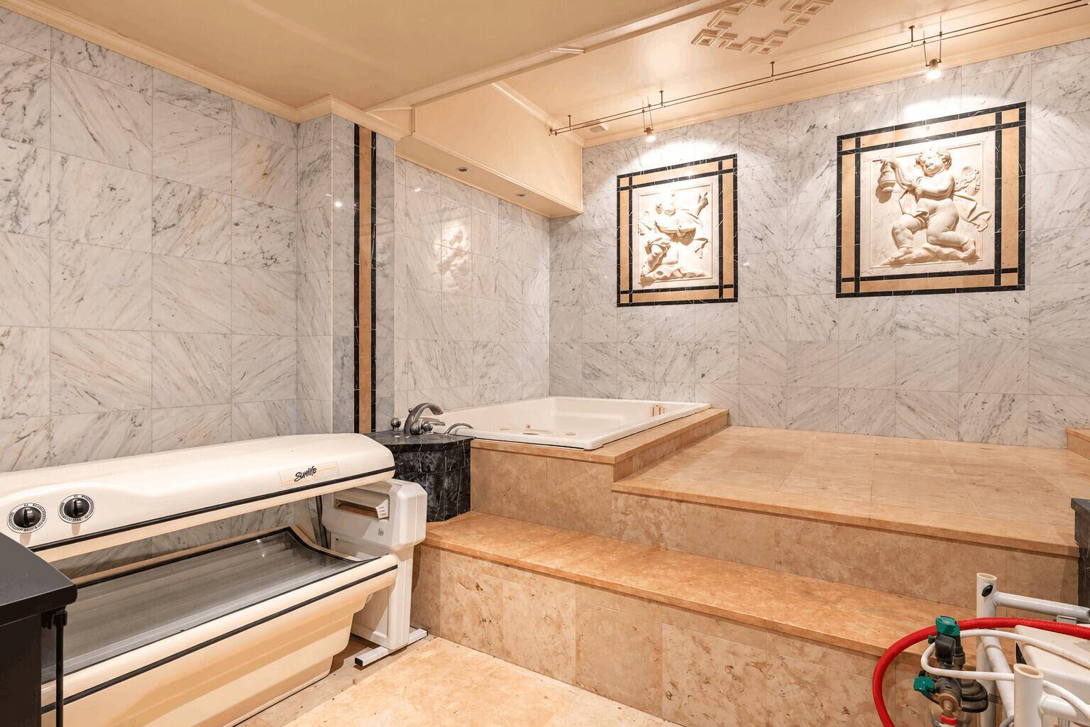 Wellnessbereich mit Solarium, Whirlpool und Marmorfliesen für private Entspannung.