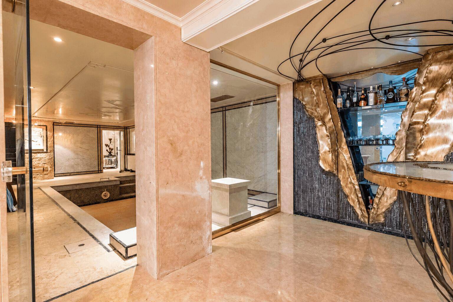 Exklusiver Wellnessbereich mit Bar, Marmorboden und Zugang zu Pool und Whirlpool.