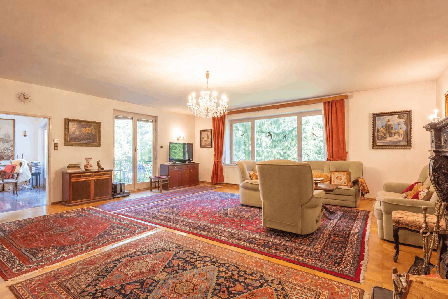 Geräumiges Wohnzimmer mit Parkettboden, Kamin und mehreren orientalischen Teppichen.