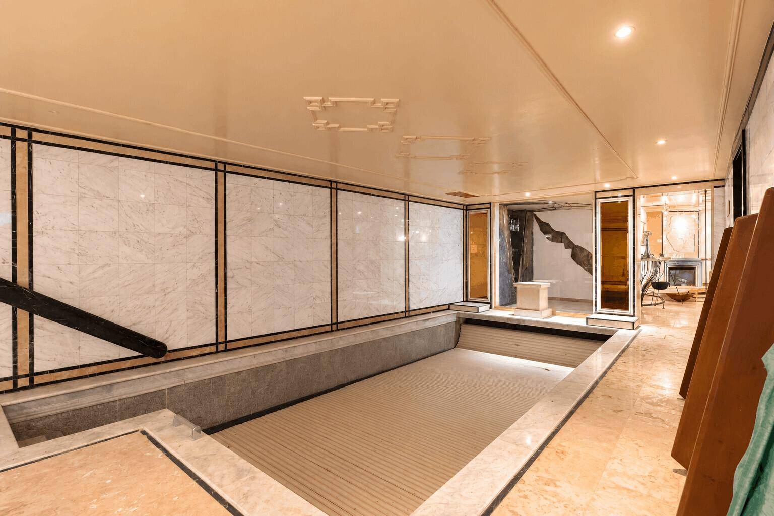 Innenpoolbereich mit Marmorverkleidung und eleganter Deckenbeleuchtung für Entspannung.