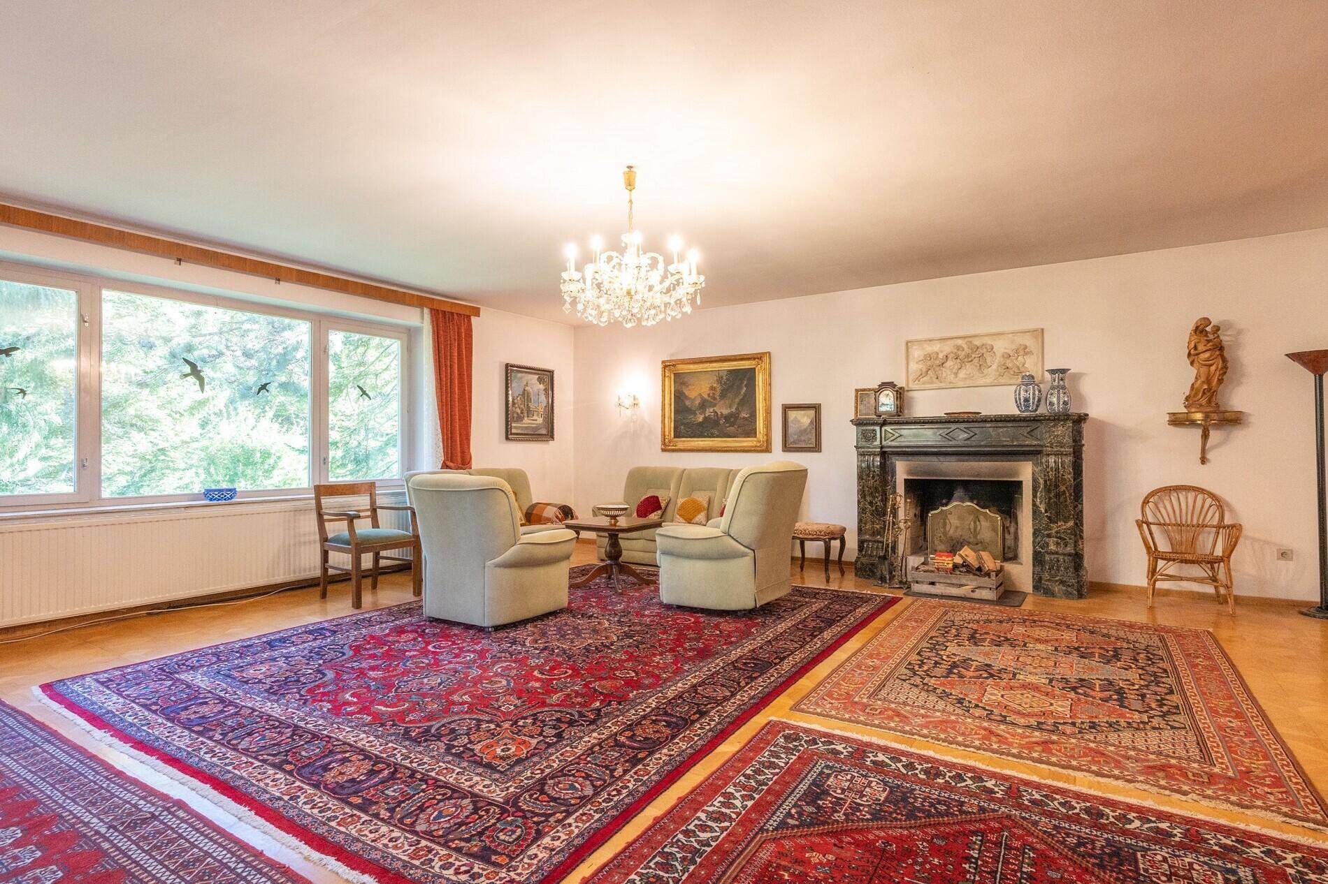 Geräumiges Wohnzimmer mit Parkettboden, Kamin und mehreren orientalischen Teppichen.