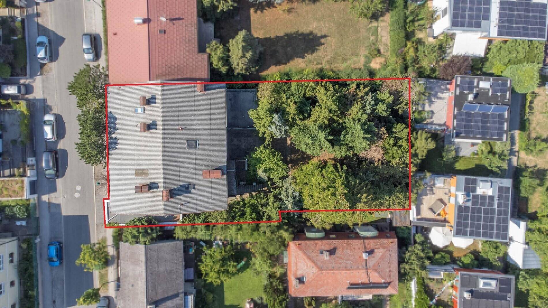 Luftaufnahme eines Wohnhauses mit großem Garten und angrenzender Straße, umgeben von viel Grün.
