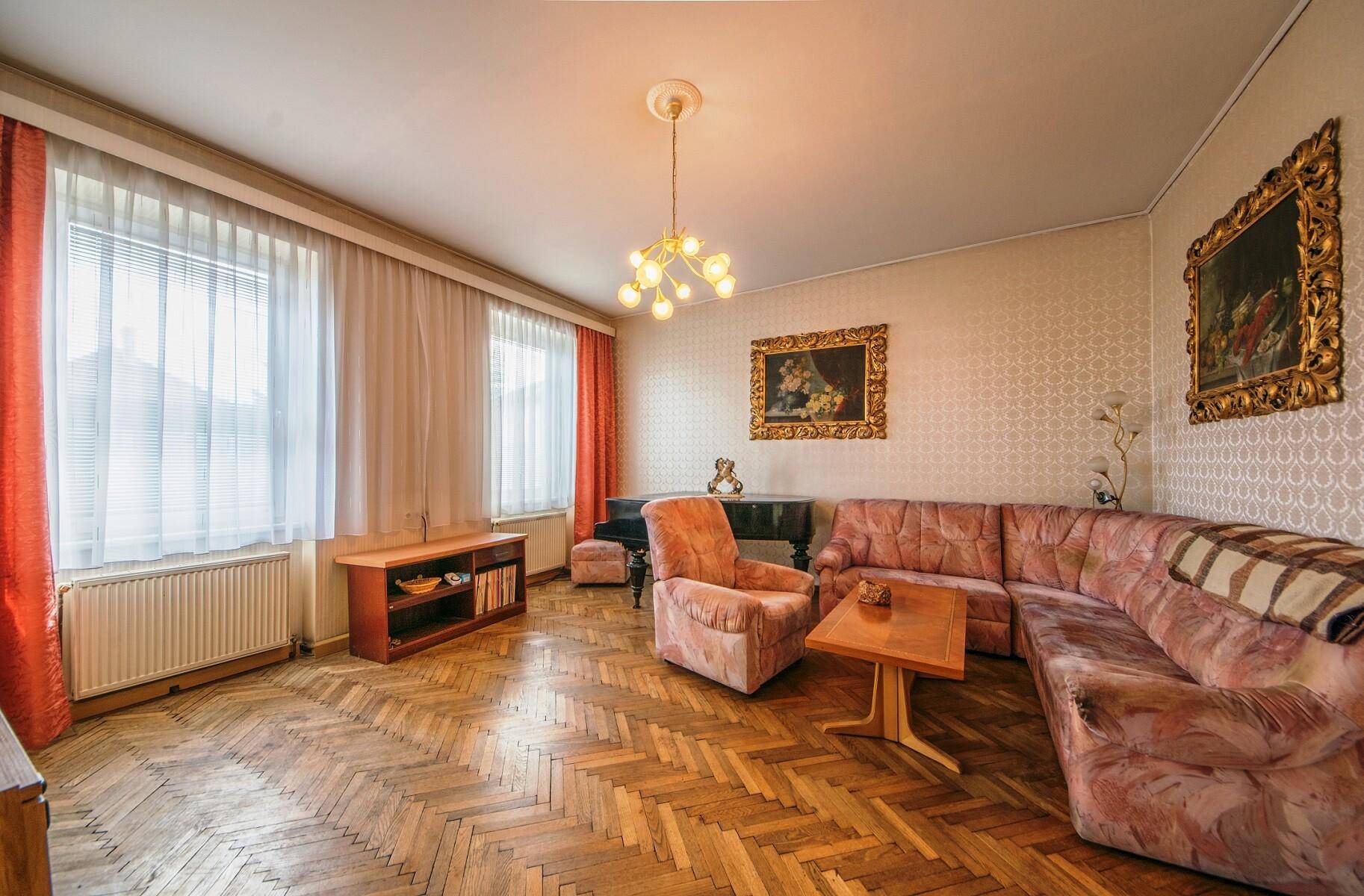 Geräumiges Wohnzimmer mit Fischgrätparkett, bequemen Sofas und großen Fenstern.