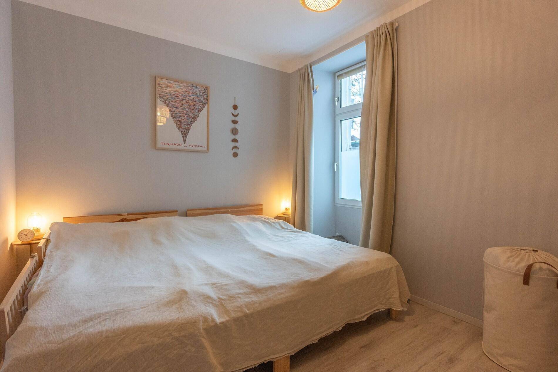 Gemütliches Schlafzimmer mit Doppelbett, hellem Laminatboden und natürlichem Lichteinfall durch das Fenster.