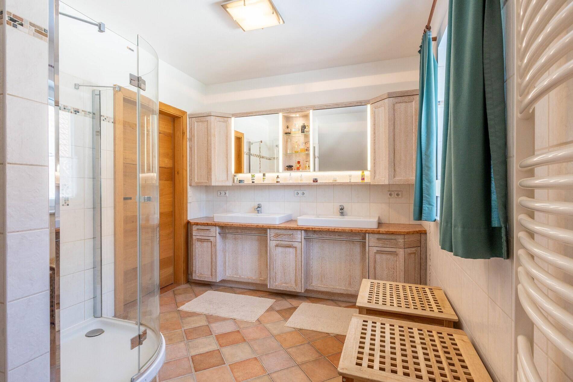 Geräumiges Badezimmer mit Dusche, Doppelwaschbecken und Terrakotta-Fliesenboden.