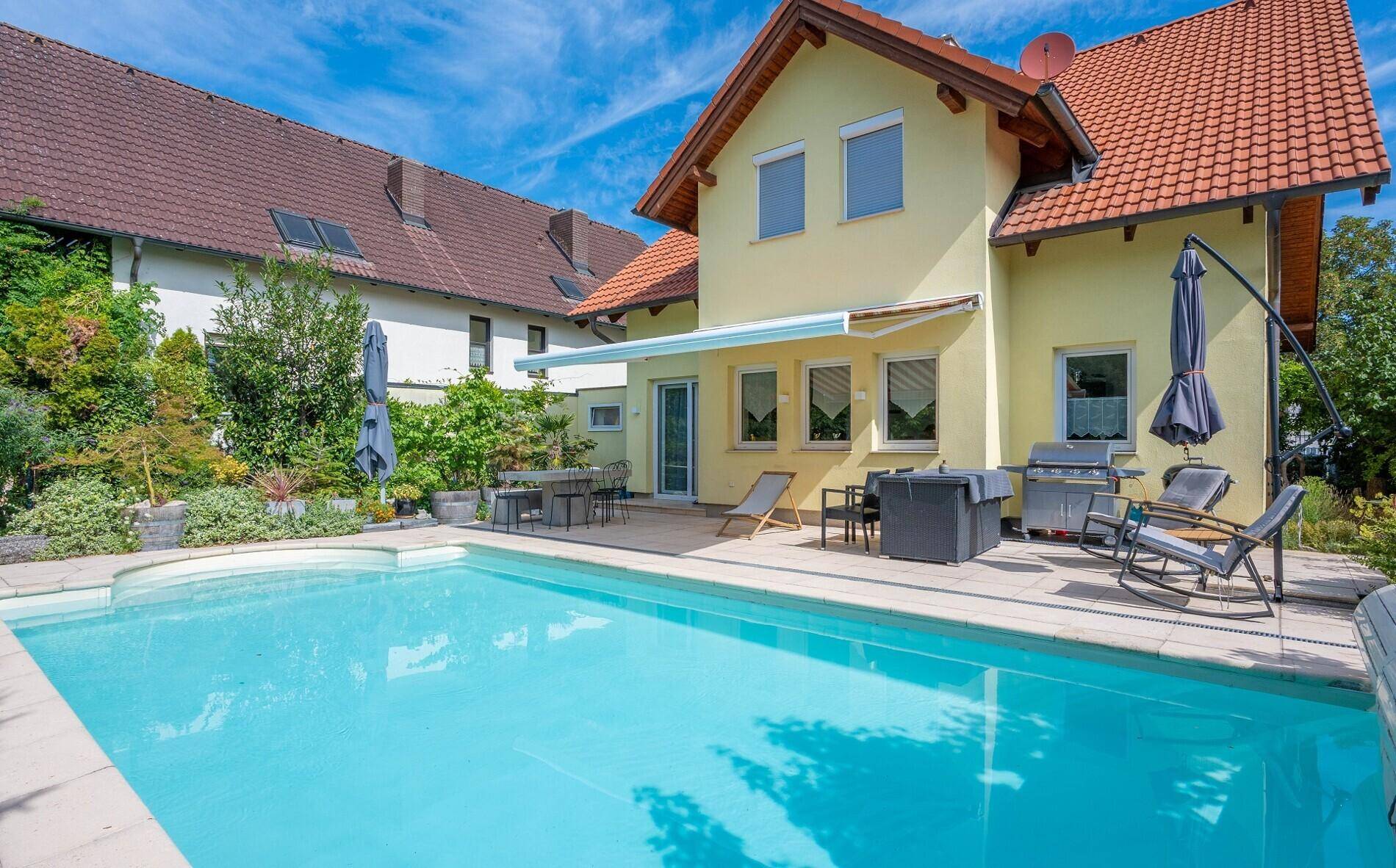 Attraktiver Außenbereich mit Swimmingpool, Sonnenterrasse und Gartenanlage am Haus.
