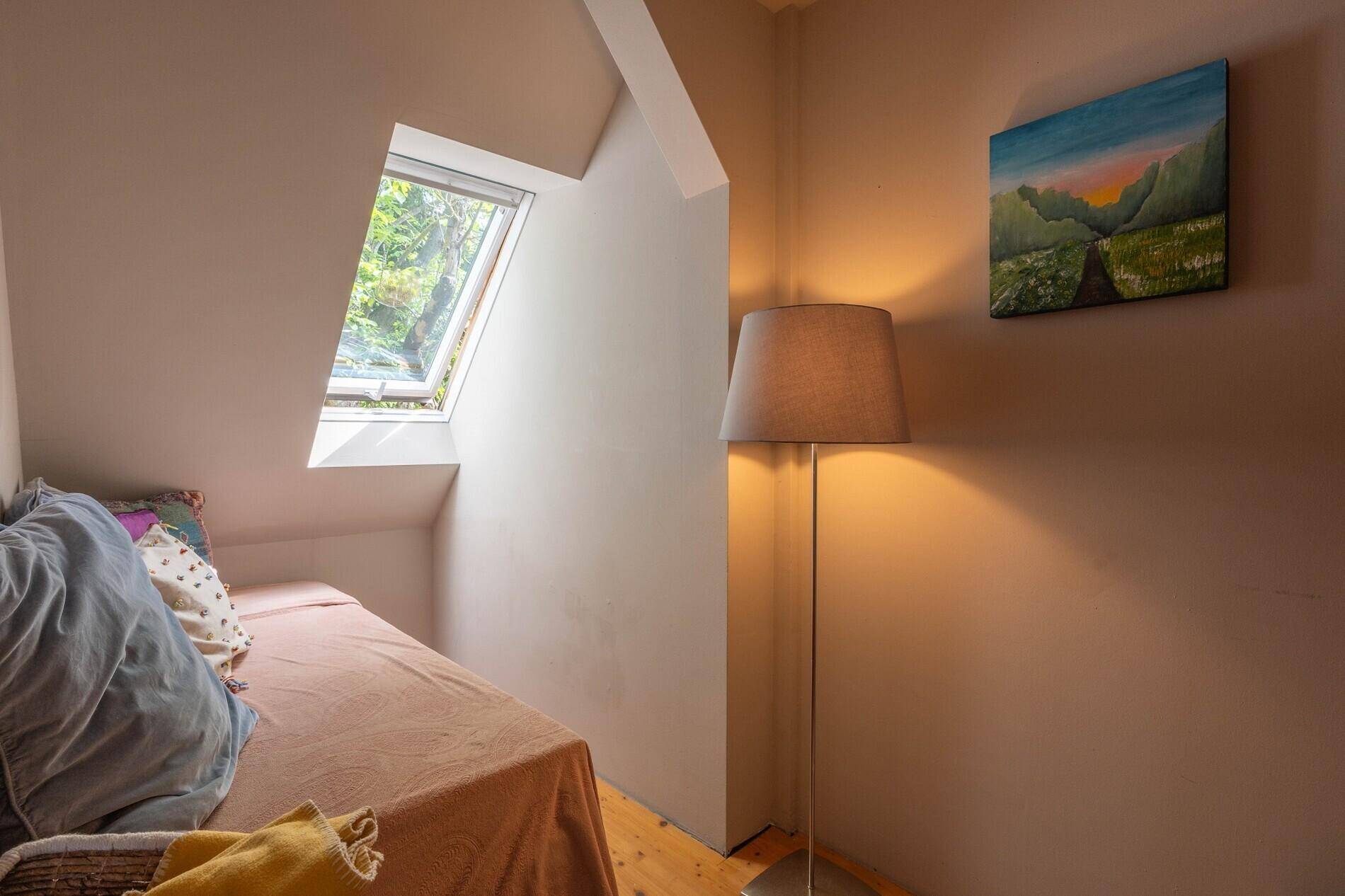 Kleines Schlafzimmer im Dachgeschoss mit Dachfenster und Holzboden.