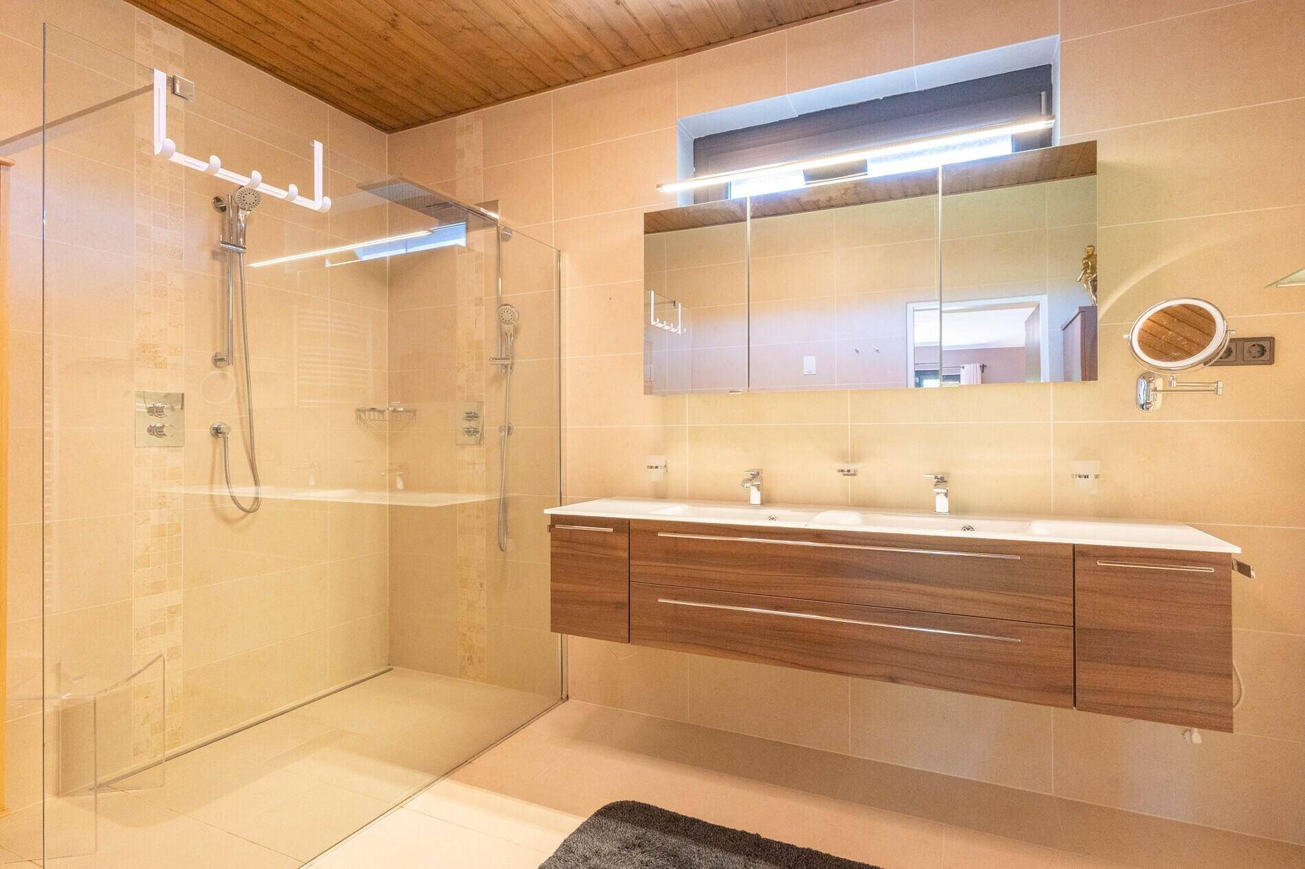 Modernes Badezimmer mit begehbarer Dusche, Doppelwaschbecken und Holzdecke.