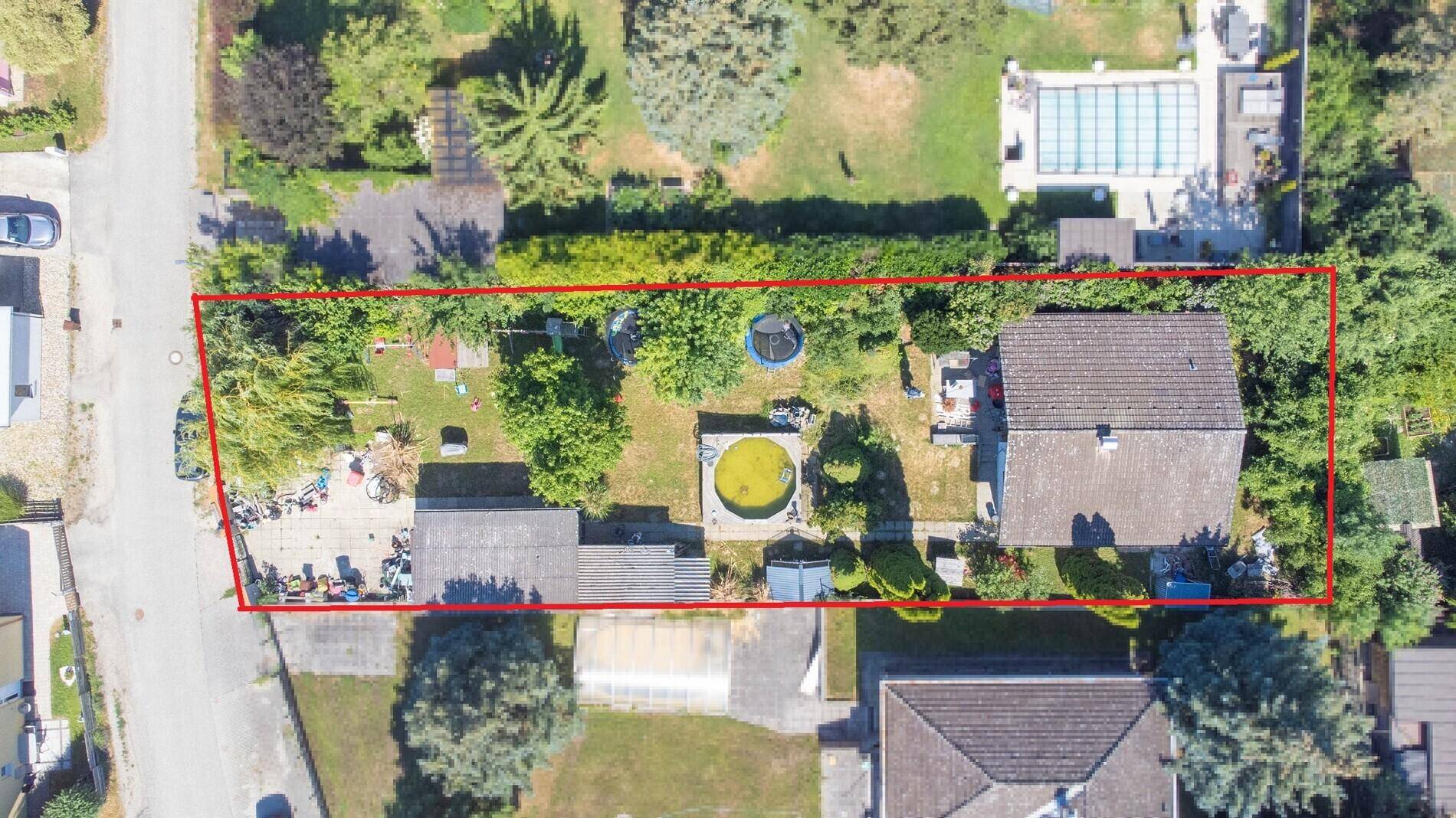 Luftaufnahme des Grundstücks mit Haus, Garten, Pool und umrandeter Fläche.