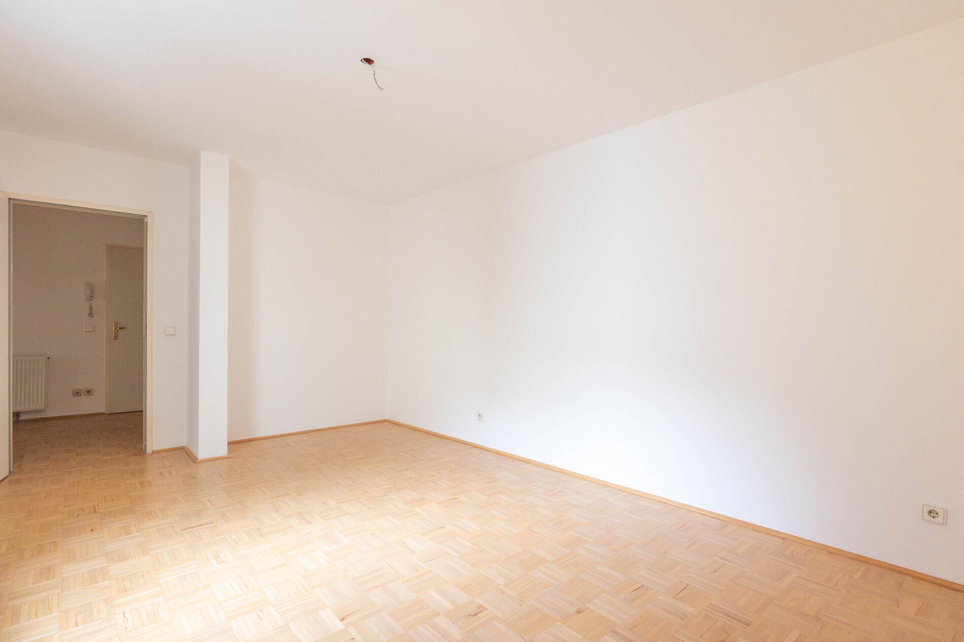 Geräumiges Zimmer mit hellem Parkettboden und weißen Wänden, vielseitig nutzbar als Wohn- oder Schlafzimmer.