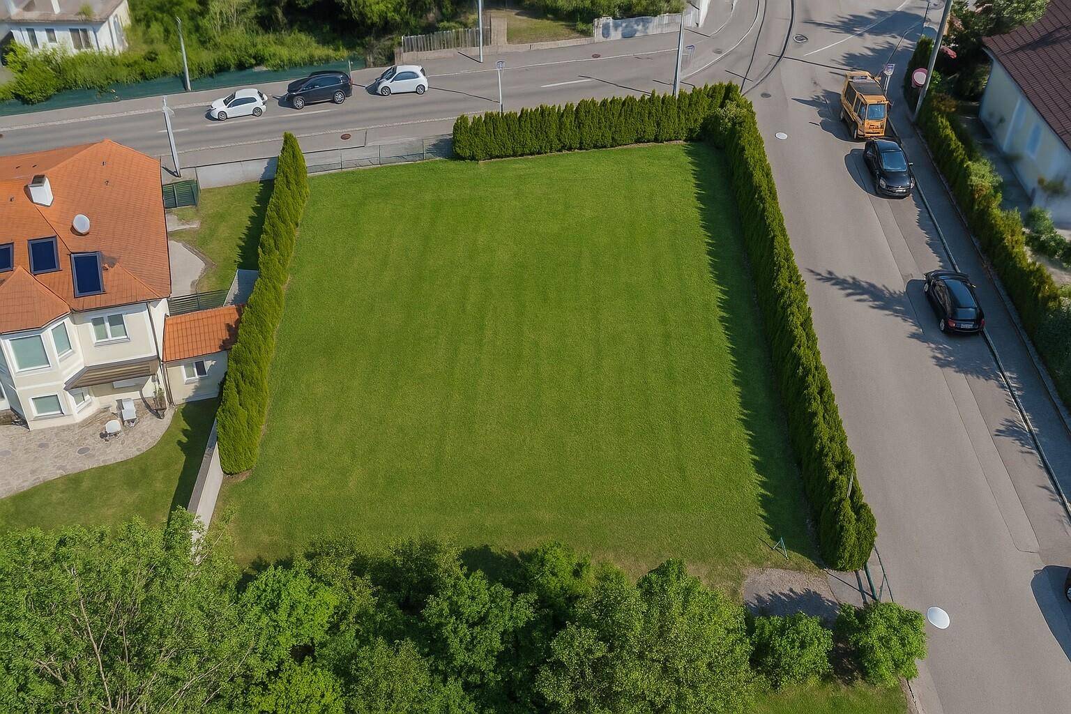Luftaufnahme eines rechteckigen Grundstücks mit Rasenfläche, Hecken und angrenzenden Straßen.