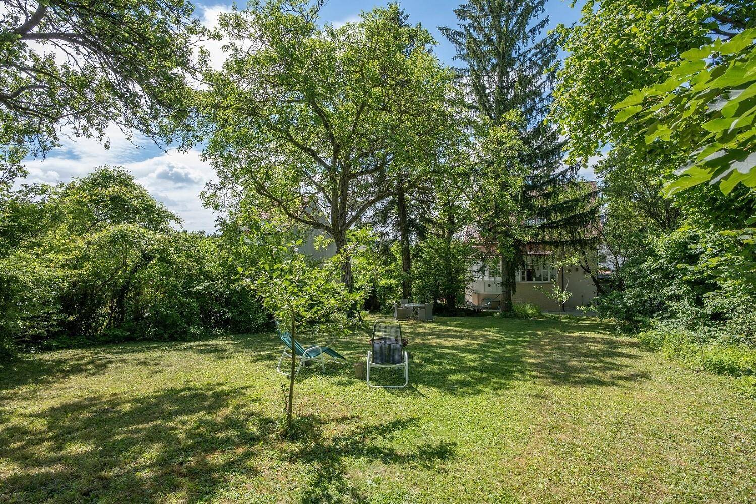 Weitläufiger Gartenbereich mit altem Baumbestand und Blick auf das charmante Wohnhaus im Hintergrund.