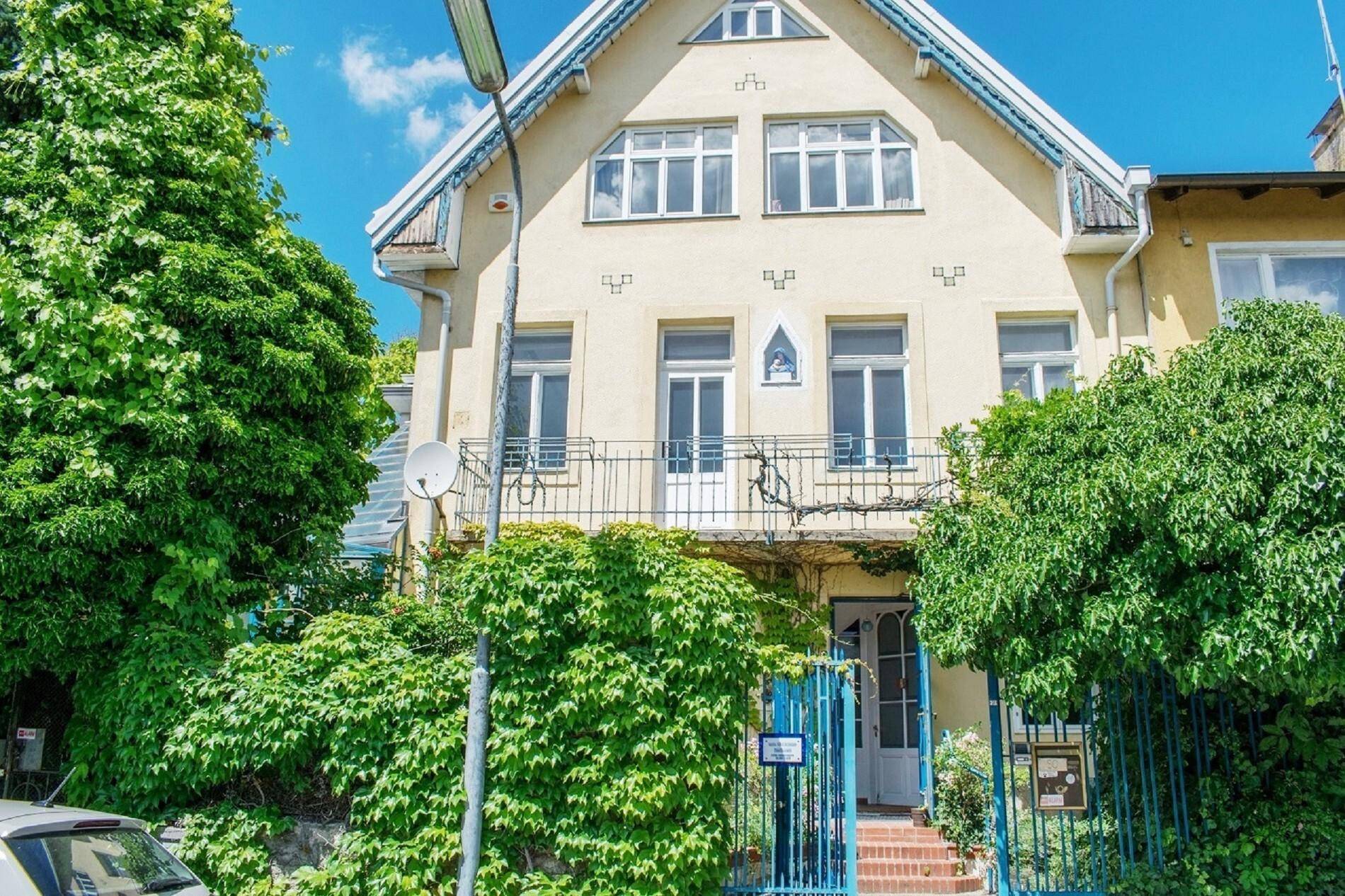 Charmante Fassade eines historischen Gebäudes mit französischen Balkonen und üppigem Efeu.