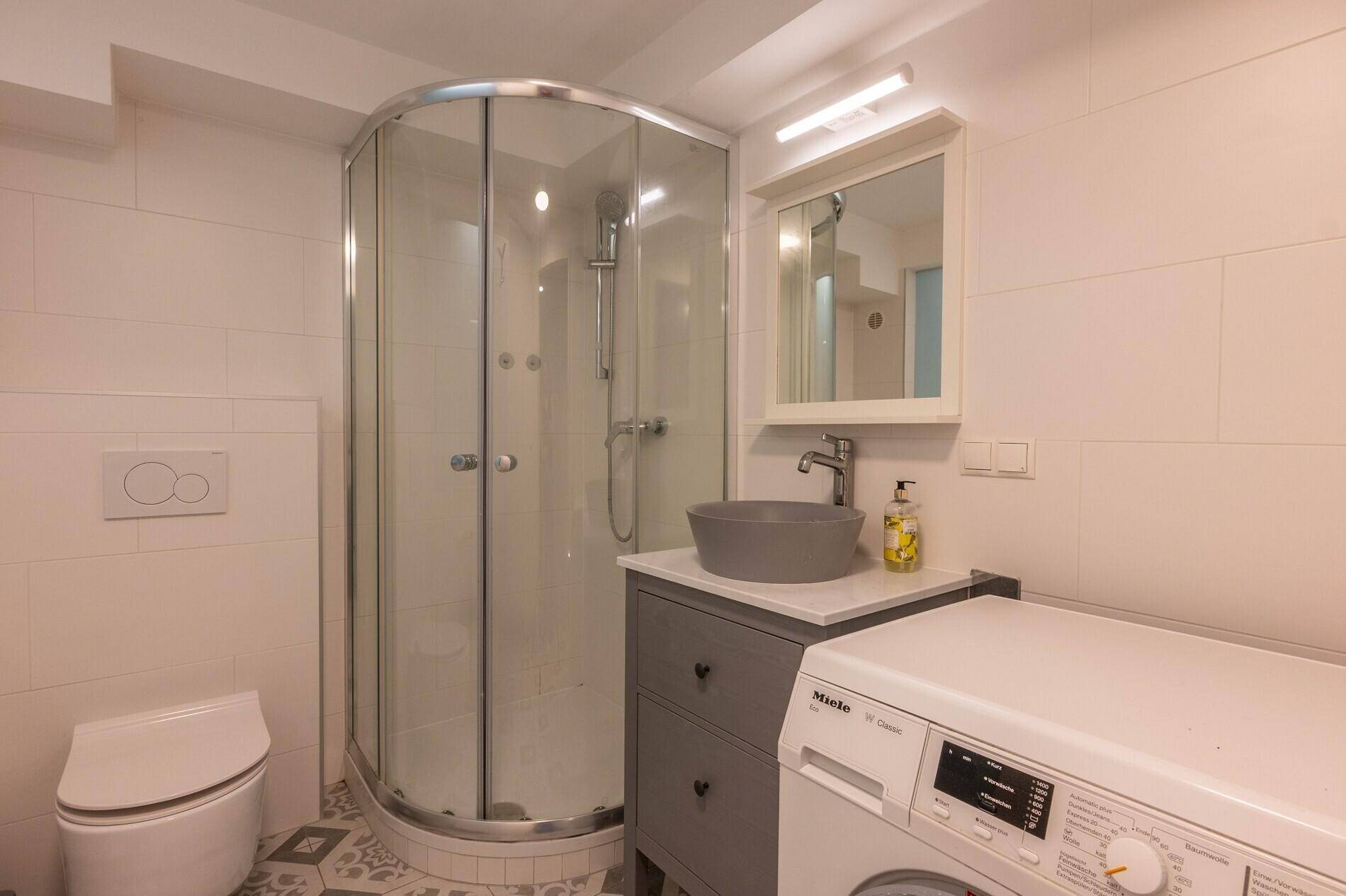 Modernes Badezimmer mit Duschkabine, Waschbecken und Waschmaschine.