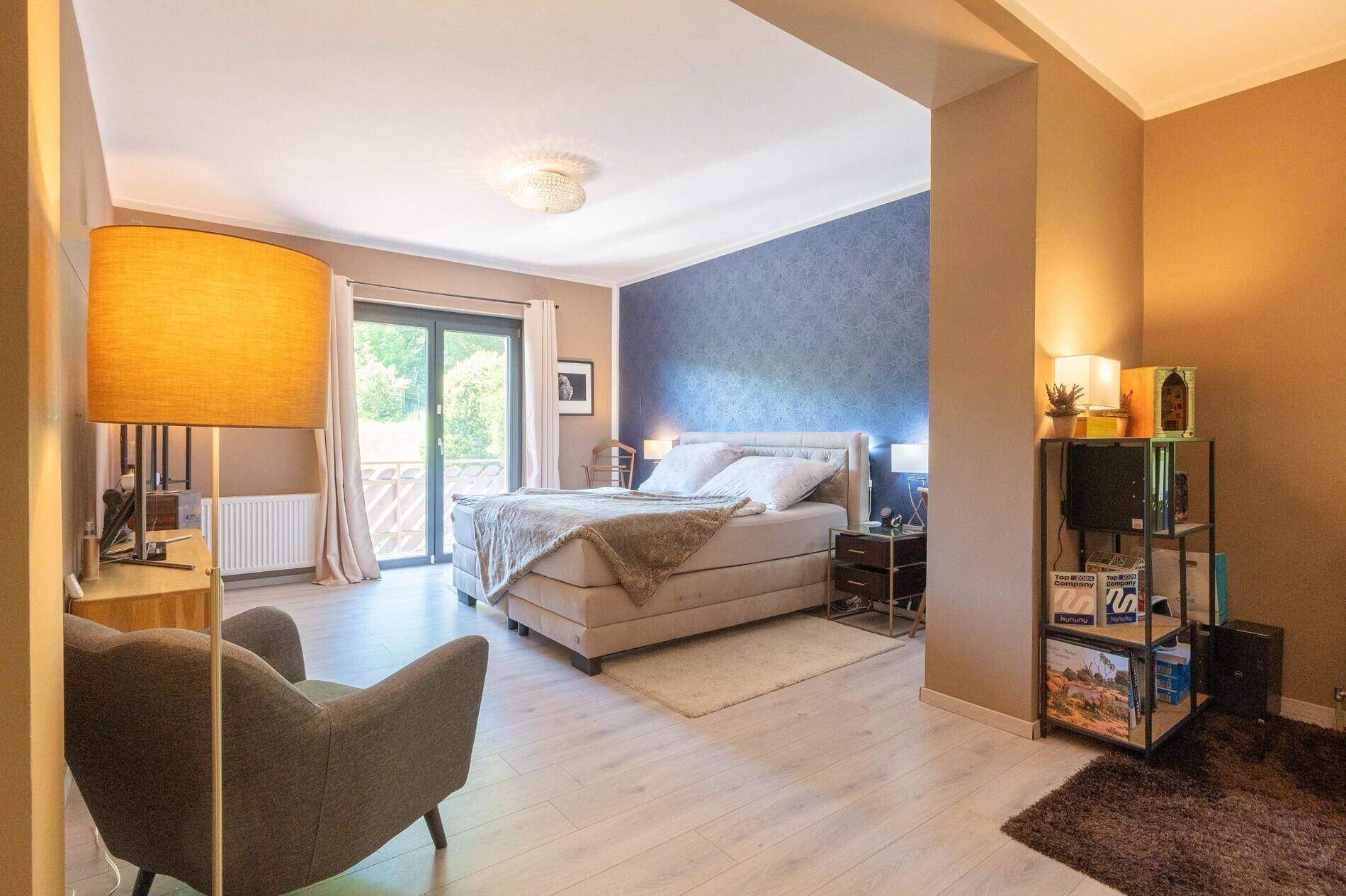 Gemütliches Schlafzimmer mit Doppelbett, hellem Holzboden und Zugang zum Balkon.