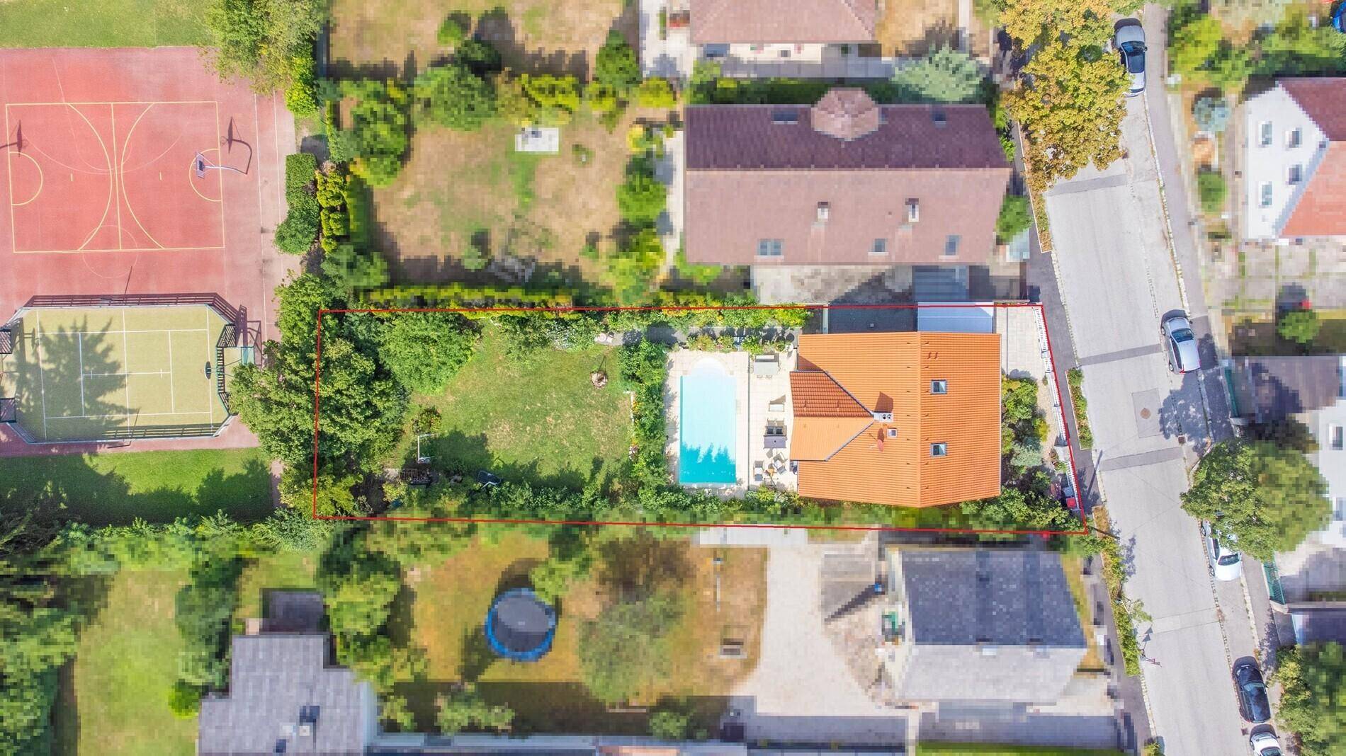 Übersichtliche Luftaufnahme des Grundstücks mit Pool, Garten und angrenzendem Sportplatz.