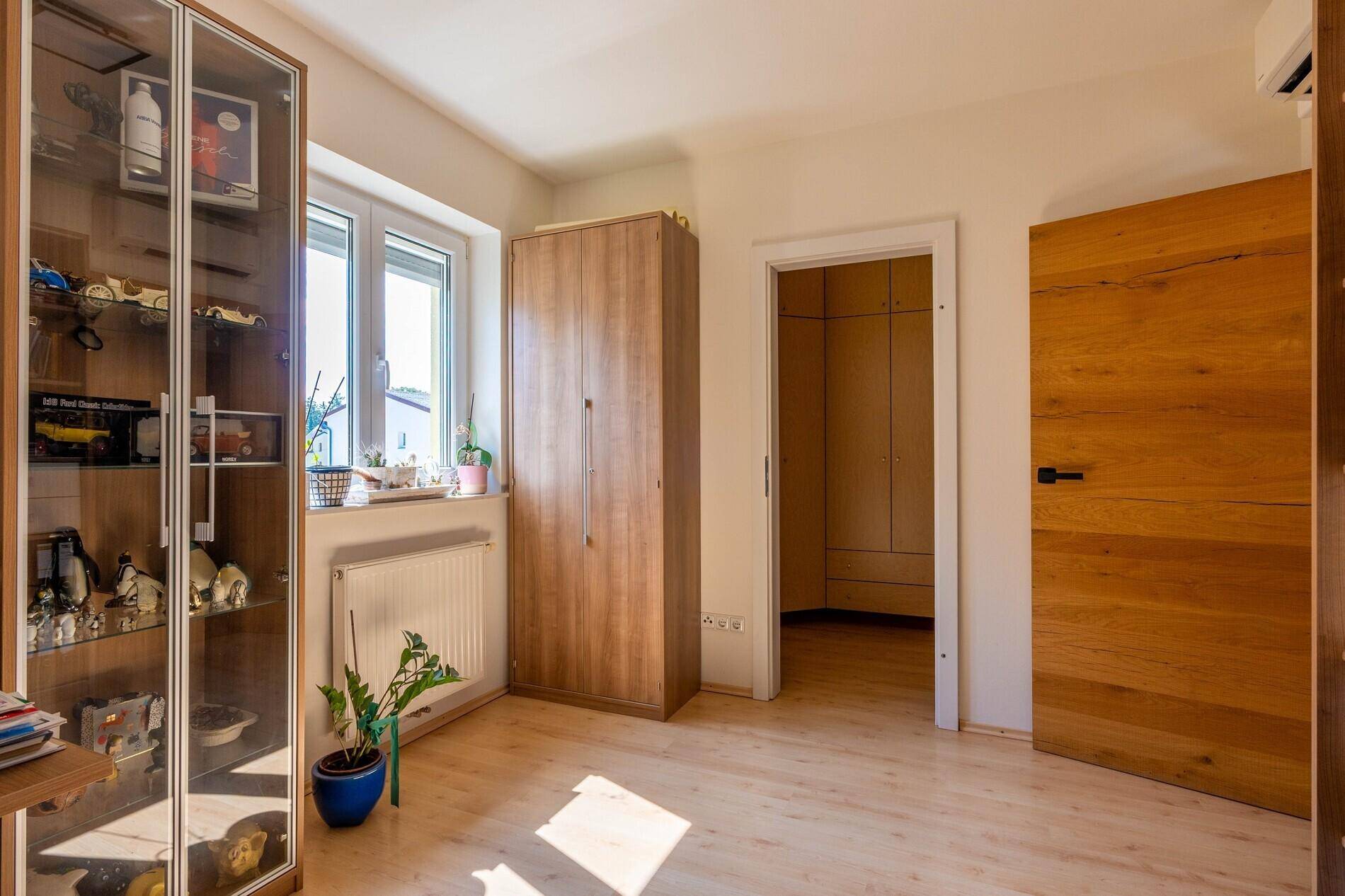 Helles Zimmer mit Laminatboden, Kleiderschrank und Zugang zu einem begehbaren Schrank.