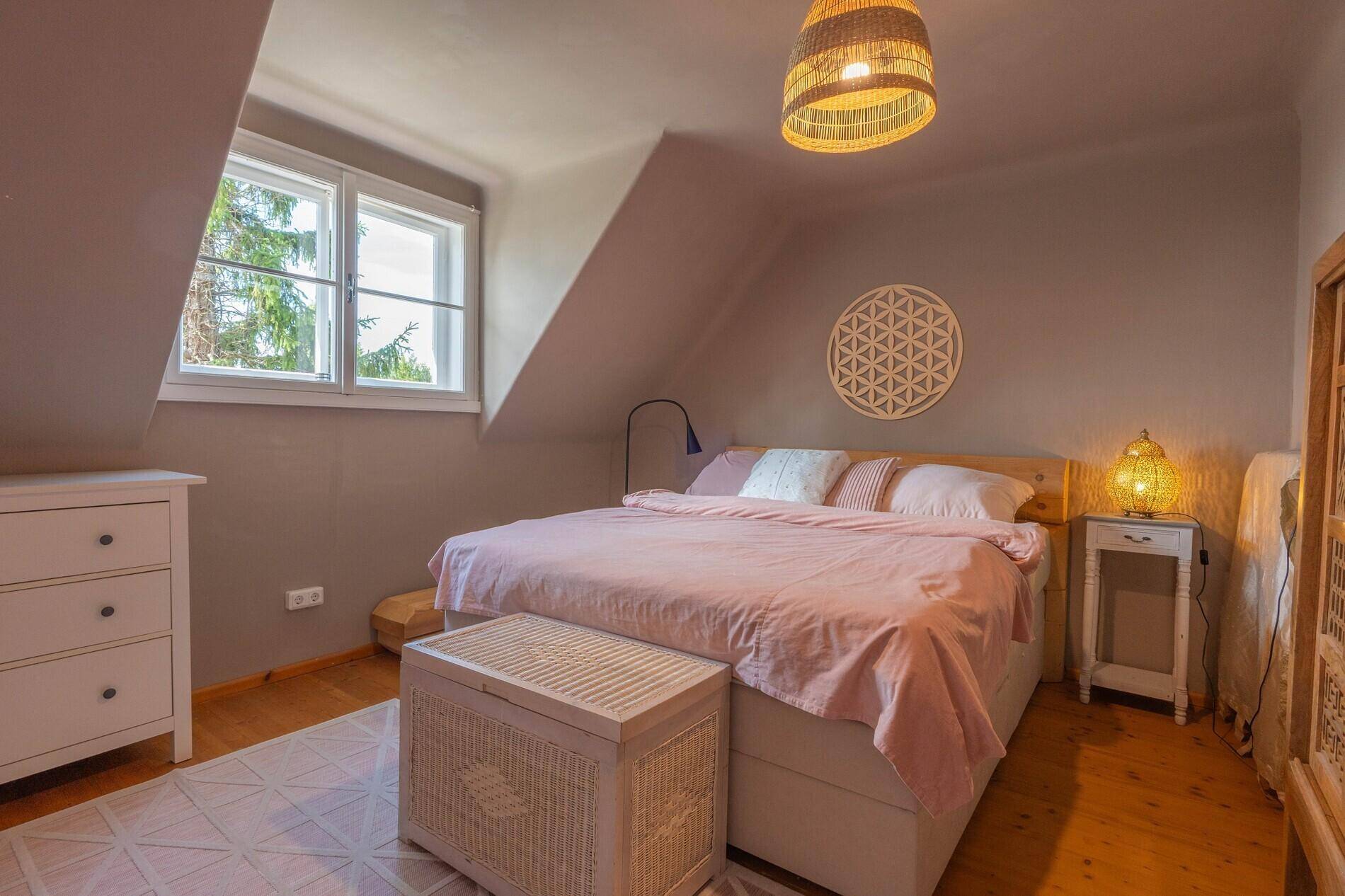Gemütliches Schlafzimmer im Dachgeschoss mit Holzboden und schrägen Wänden.