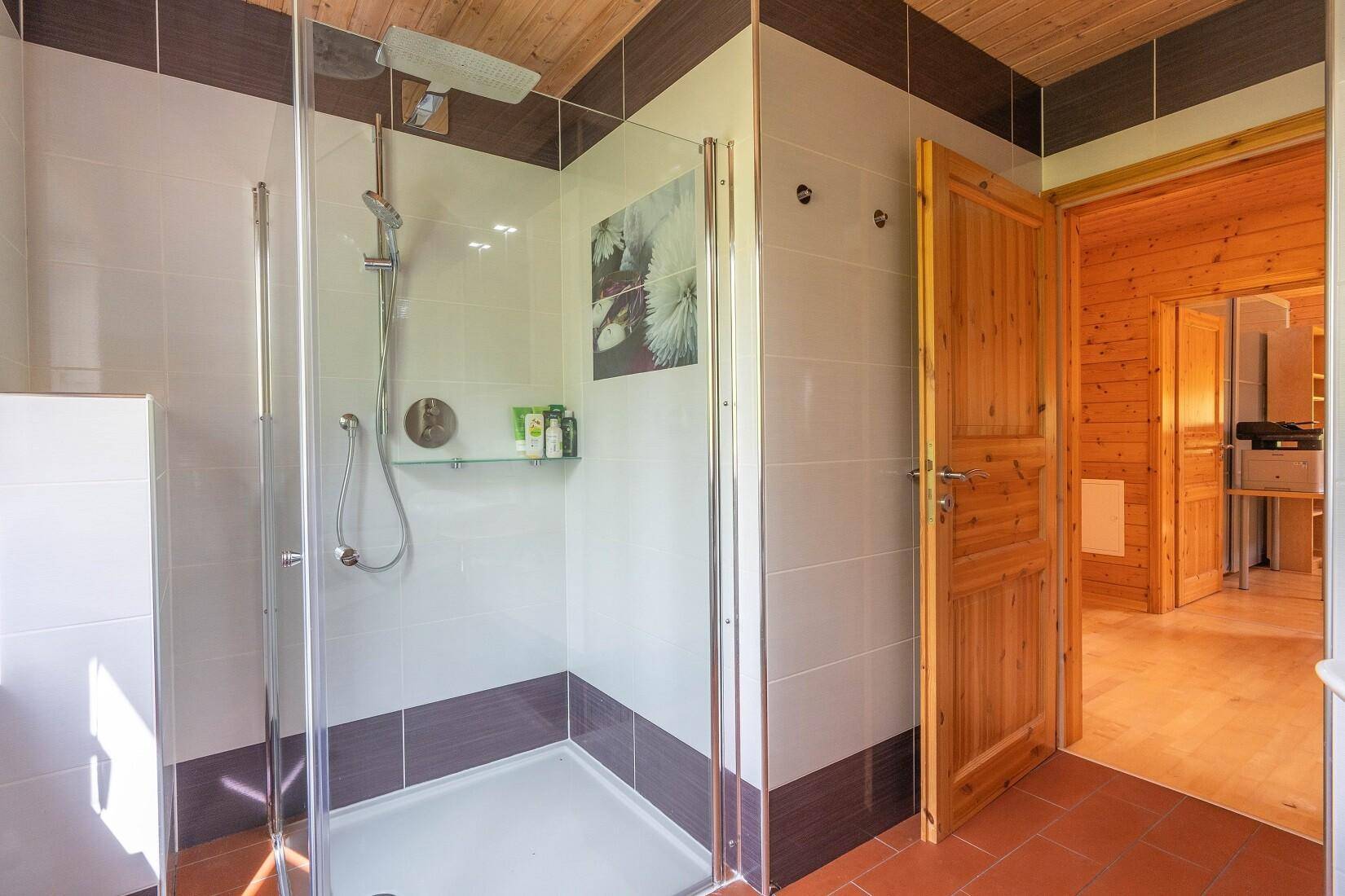 Modernes Badezimmer mit Duschkabine, weißen Fliesen und Holzwänden.