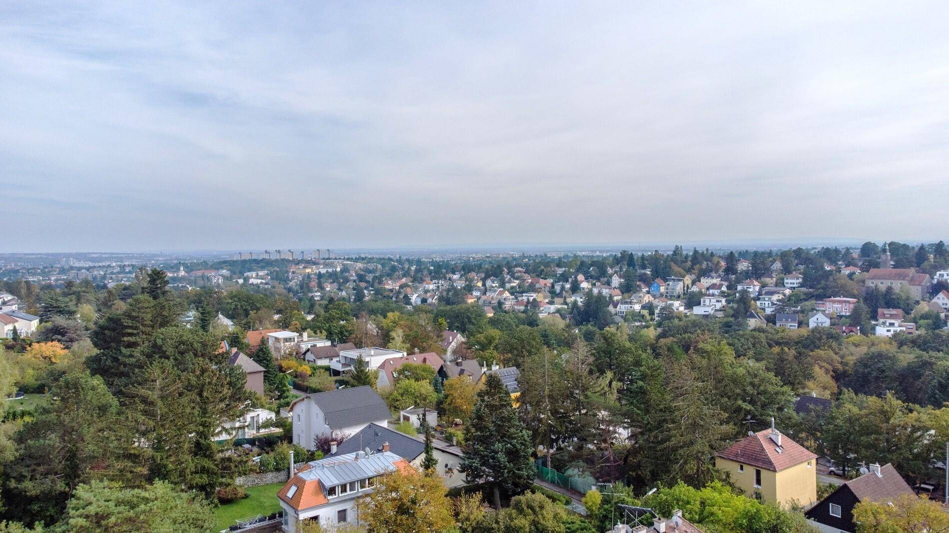 Weitläufiger Blick über die grüne Hügellandschaft mit verstreuten Wohnhäusern.