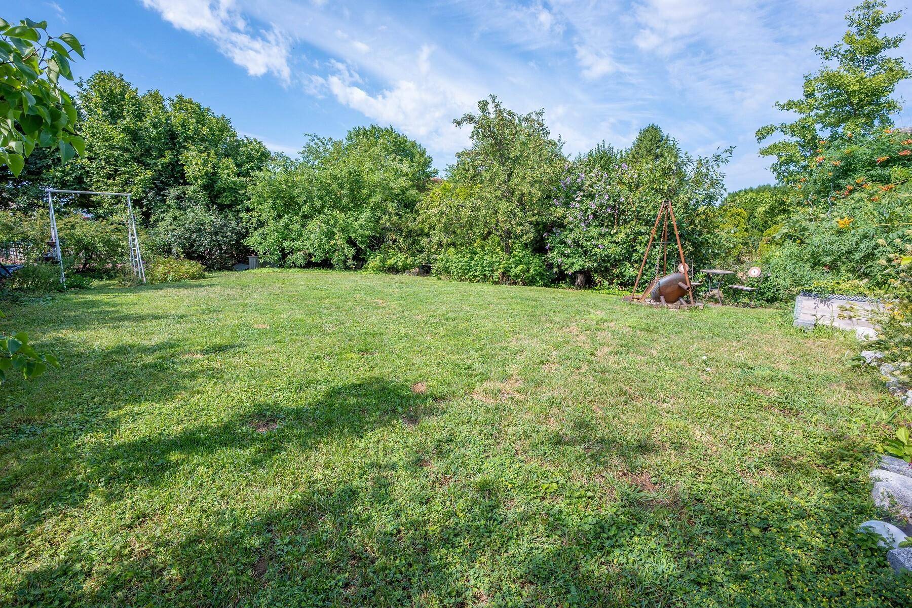 Großer, gepflegter Garten mit Rasenfläche, Bäumen und Platz für Freizeitaktivitäten.