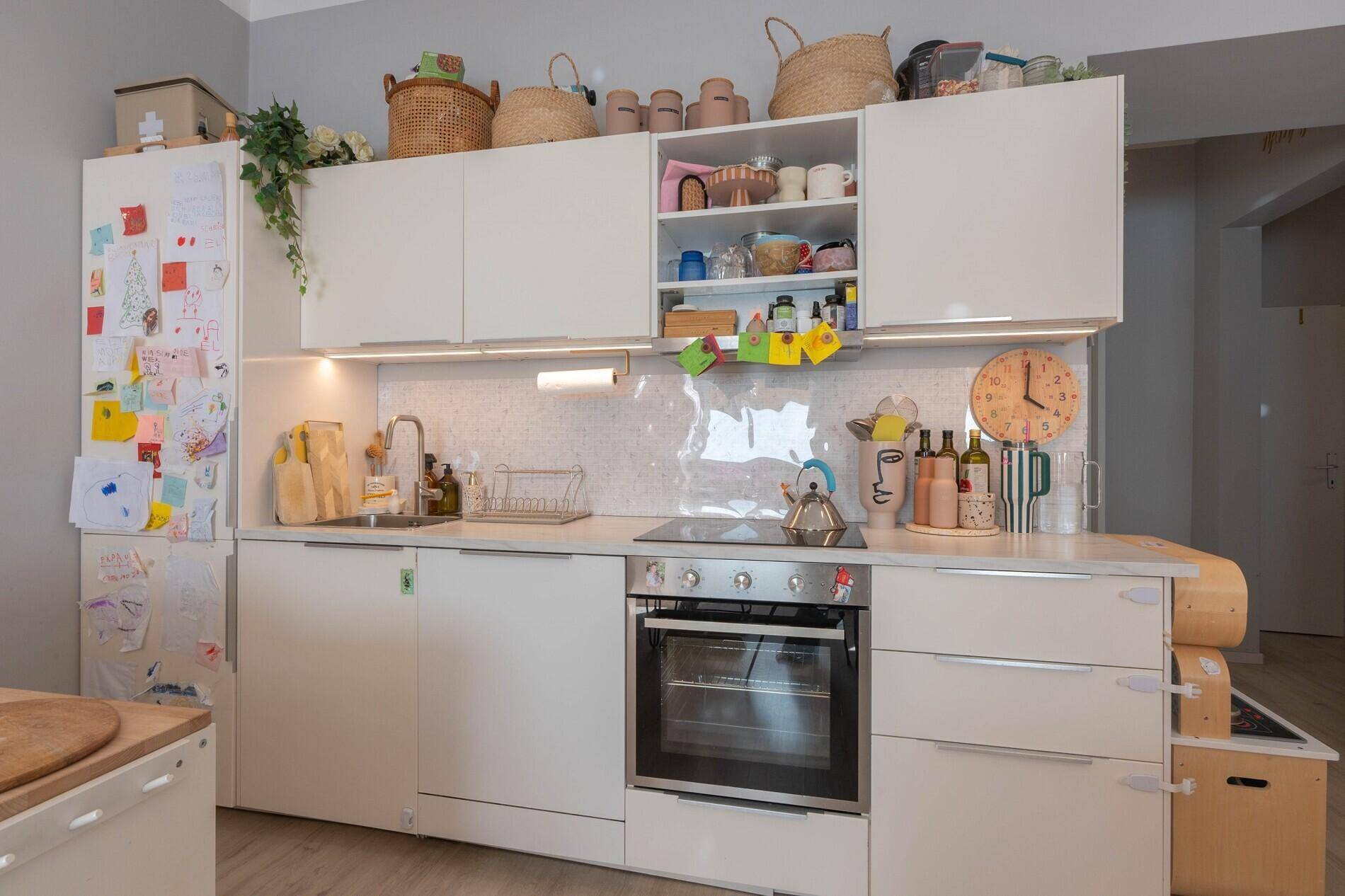 Funktionale Küche mit weißen Schränken, integriertem Backofen und heller Arbeitsplatte.