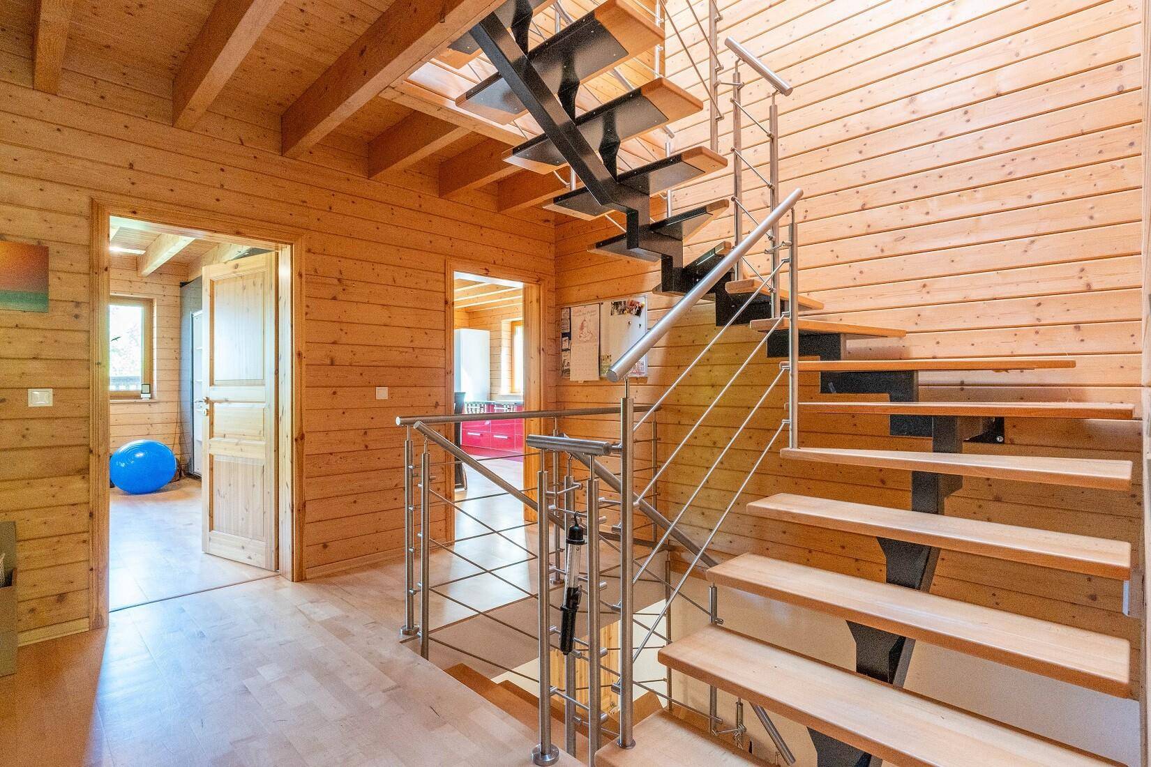 Heller Flur mit Holzvertäfelung, offener Treppe und Zugang zu weiteren Räumen.