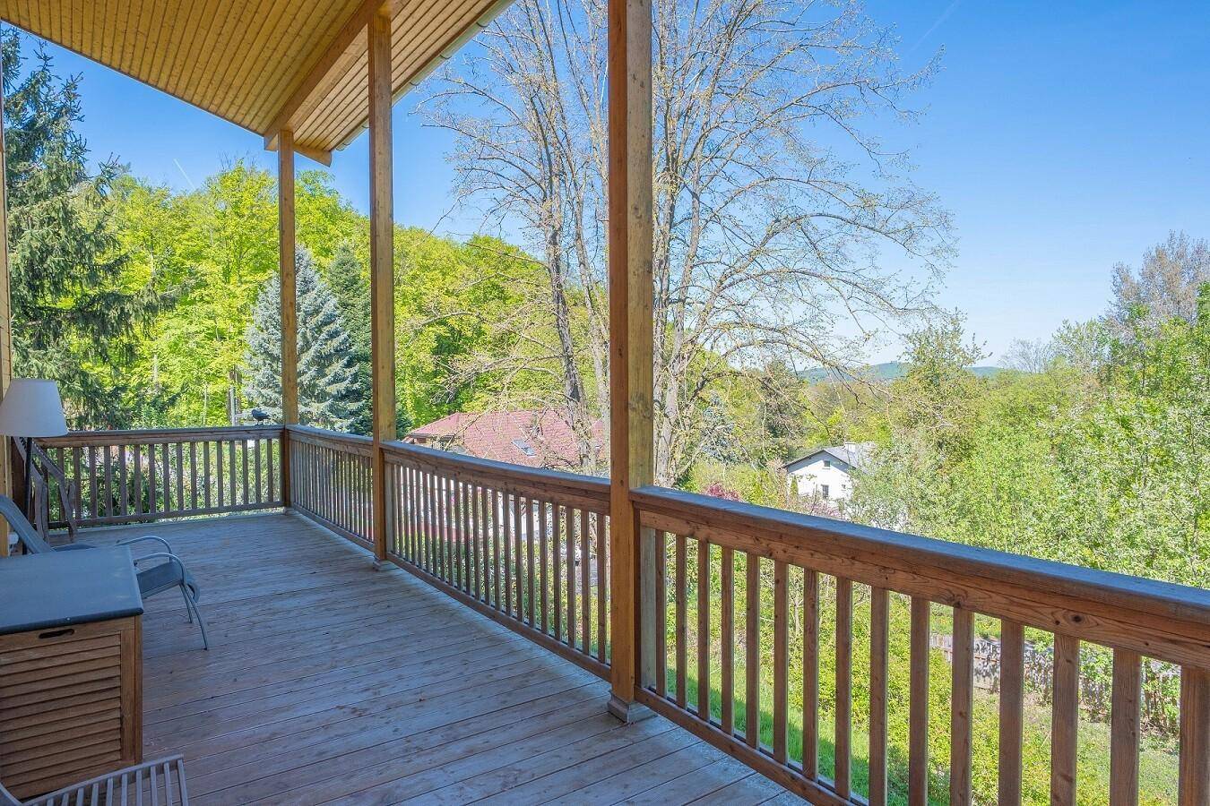 Geräumiger Holzbalkon mit Geländer und weitem Blick über die grüne Landschaft.