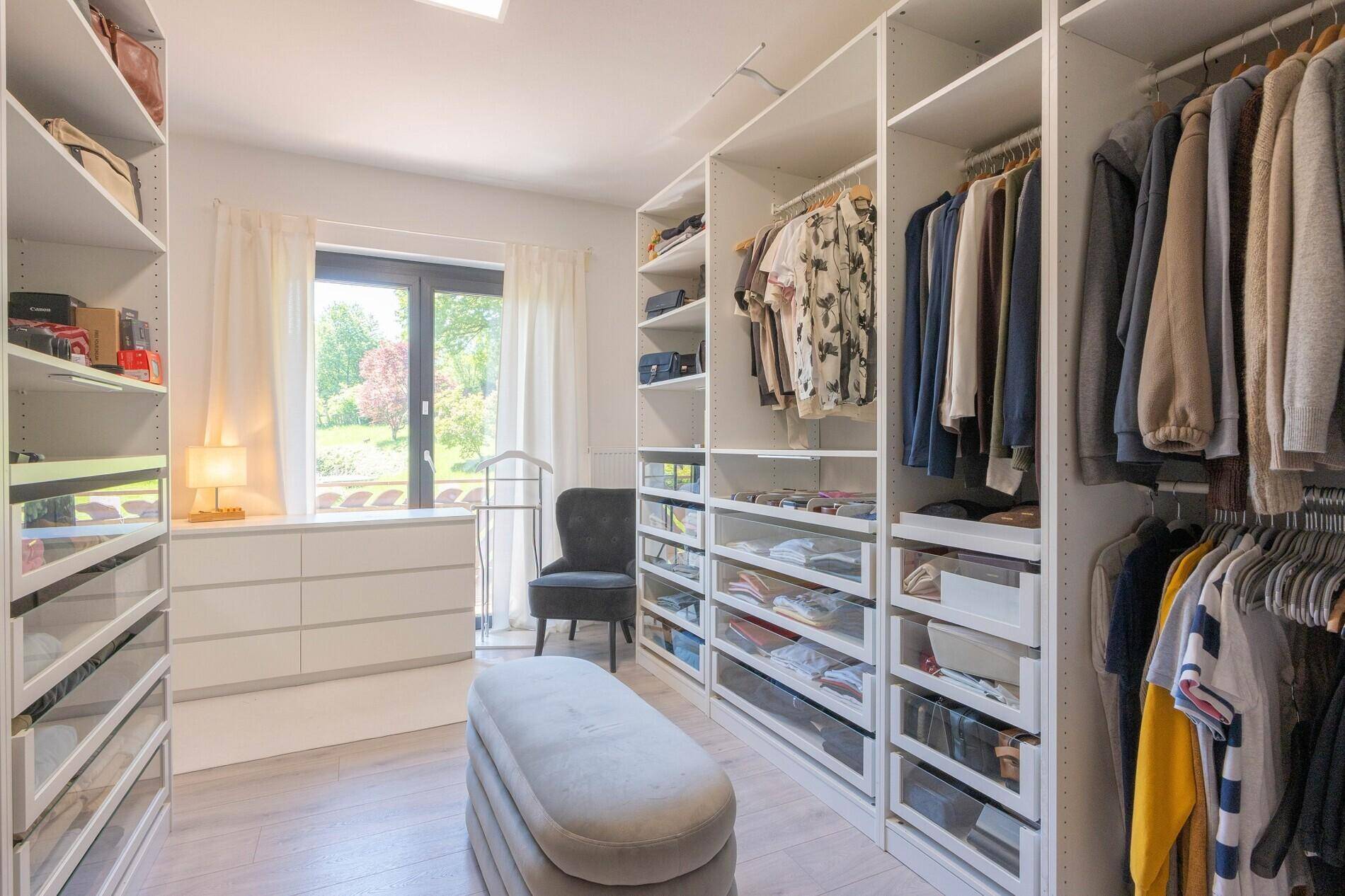Geräumiger begehbarer Kleiderschrank mit viel Stauraum und Fenster für Tageslicht.