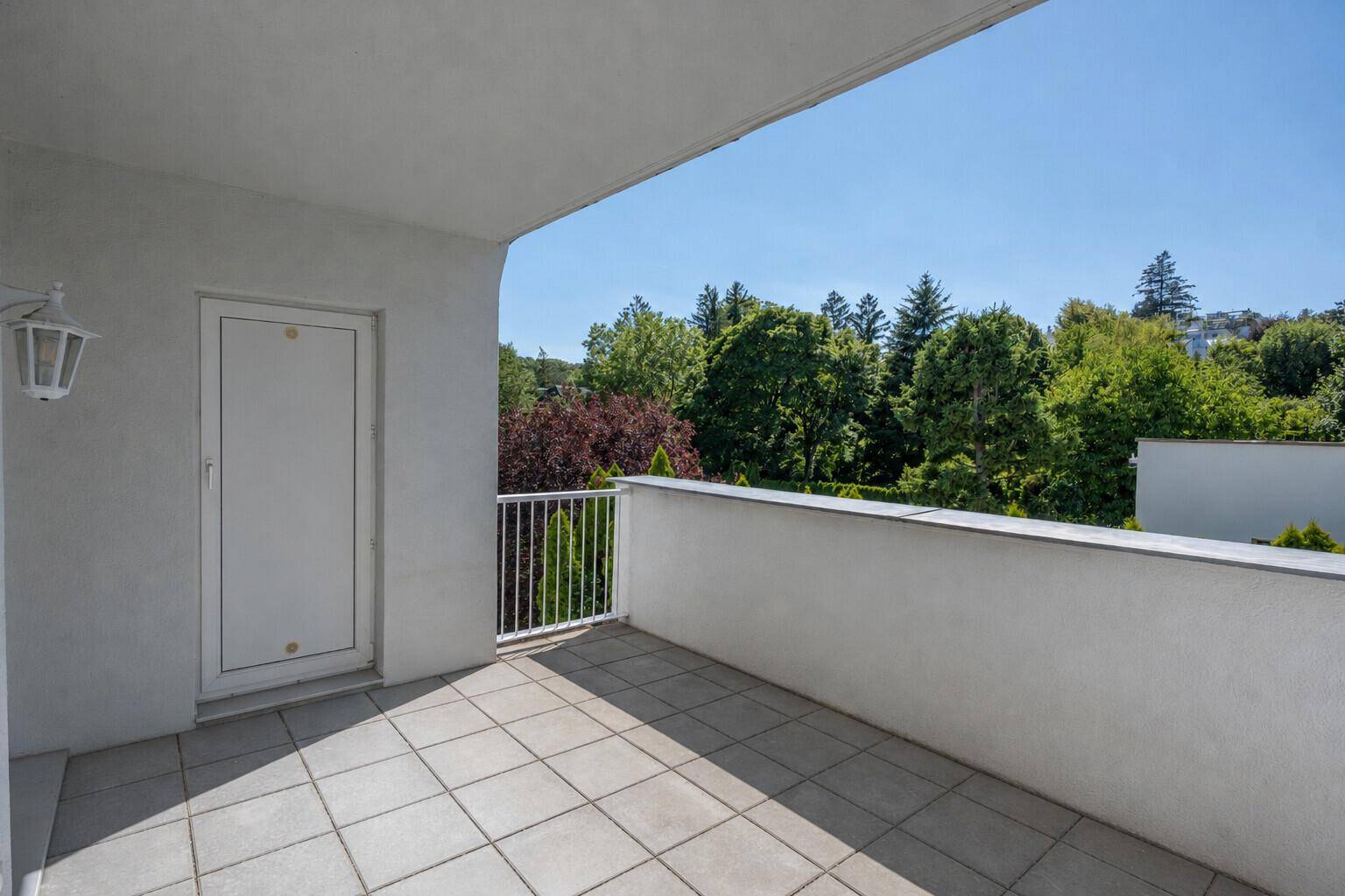 Geräumiger Balkon mit Fliesenboden und Blick auf die umliegende grüne Landschaft.