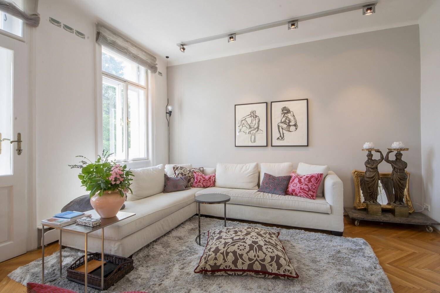 Gemütlicher Wohnbereich mit hellem Sofa, weichem Teppich und großen Fenstern für viel Tageslicht.