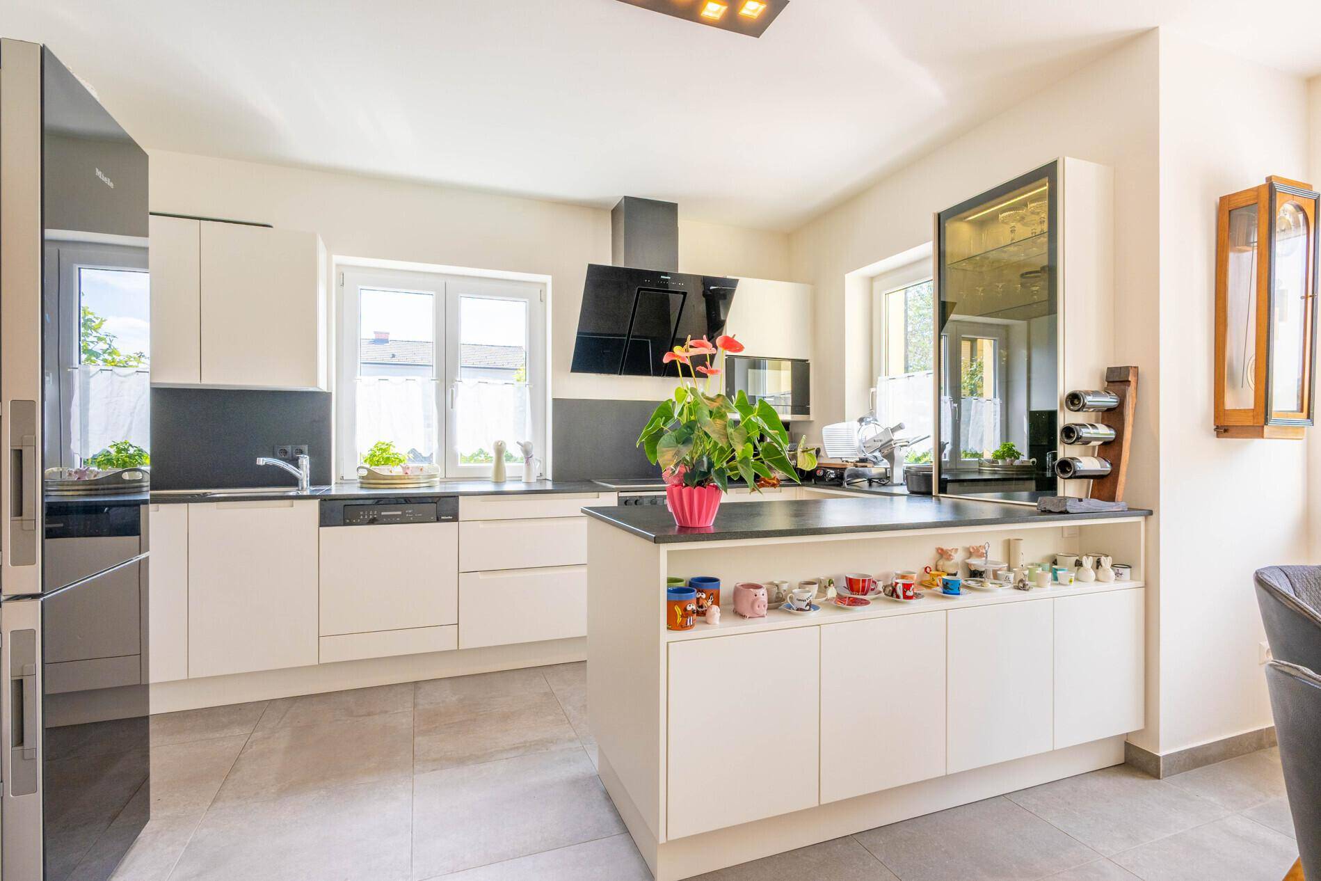 Moderne Küche mit weißen Schränken, Kücheninsel und hochwertigen Einbaugeräten.