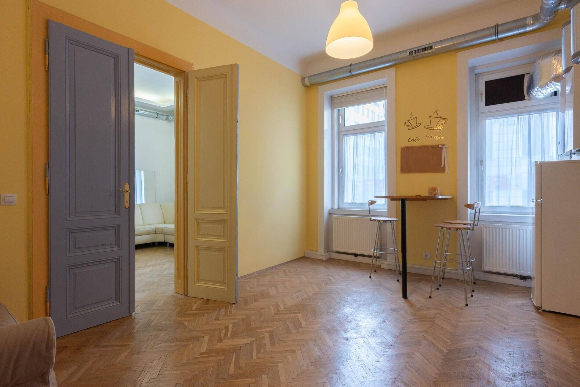 Helle Küche mit gelben Wänden, Holzboden und einem kleinen Bartisch.