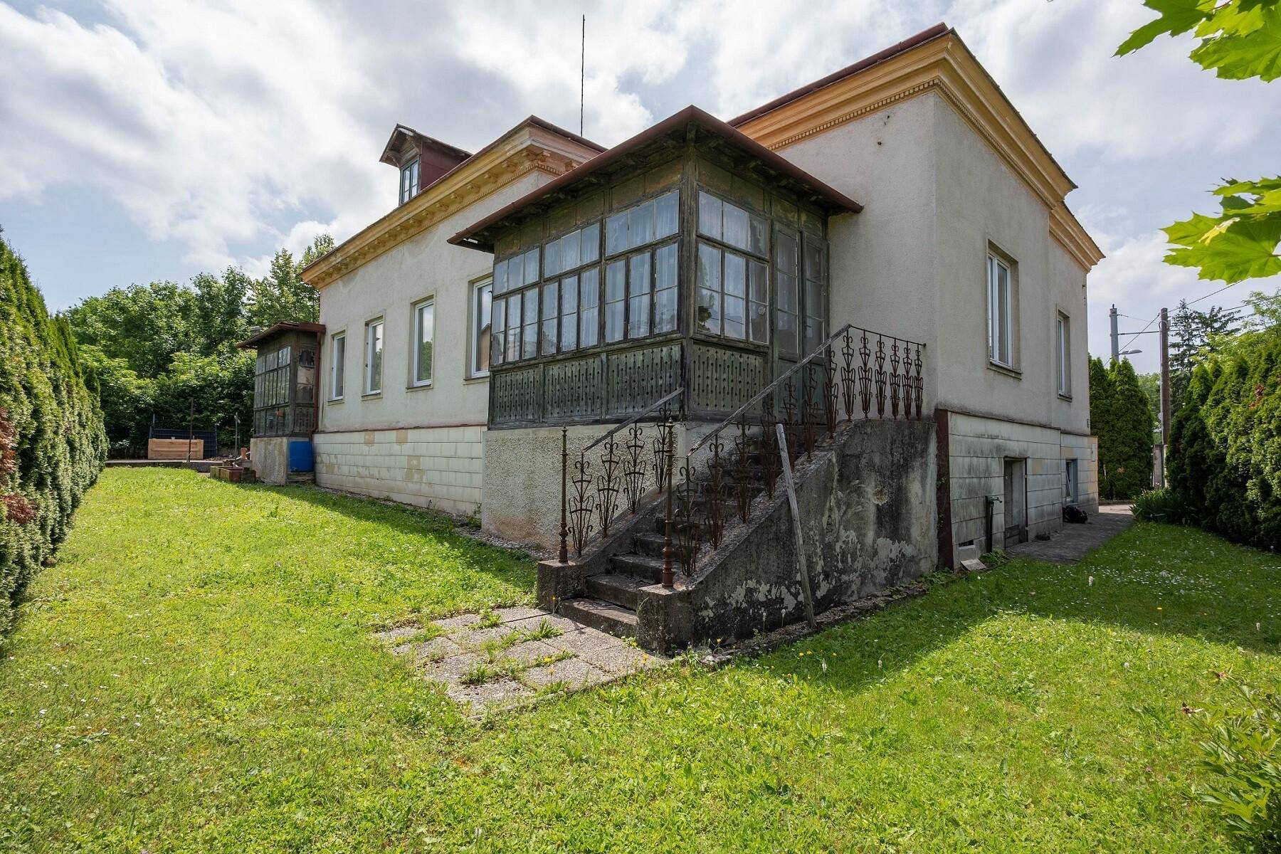 Seitenansicht des Hauses mit großem Garten und einer alten Außentreppe zum Wintergarten.