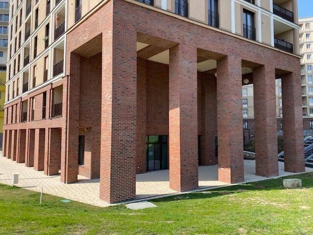 Detailansicht der modernen Ziegelfassade des Gebäudes mit markanten Säulen und einem einladenden Eingangsbereich.