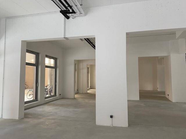 Geräumiger, unmöblierter Gewerberaum mit hohen Decken und großen Fenstern, bereit für den Ausbau.