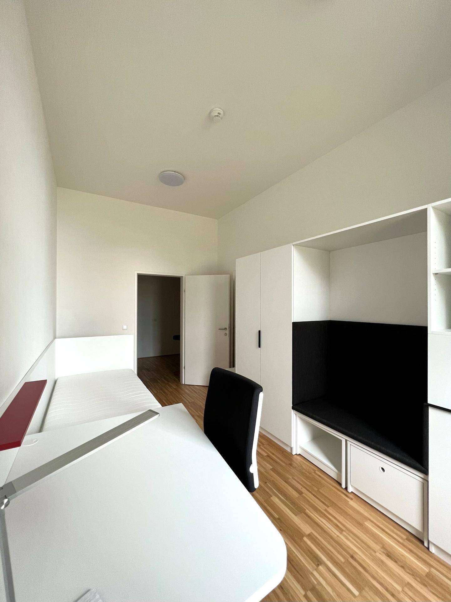 Funktionales Schlafzimmer mit Schreibtisch, Bett und integriertem Stauraum, hell und modern eingerichtet.