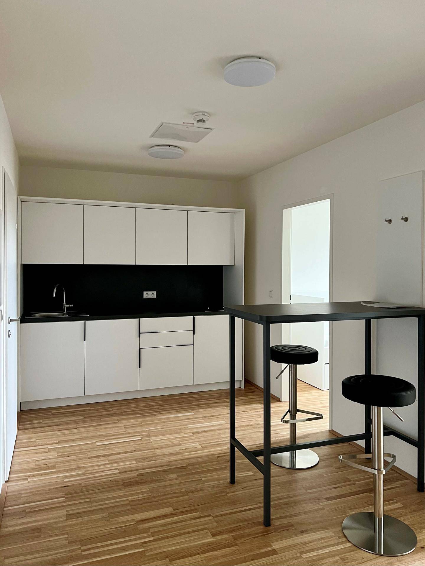 Moderne Küchenzeile mit weißen Schränken, schwarzer Arbeitsplatte und integriertem Spülbecken.